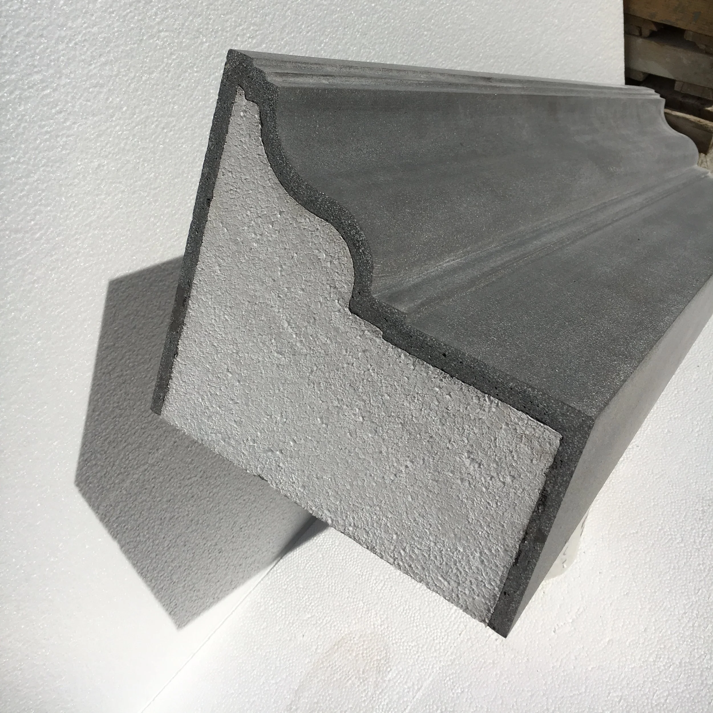 Cross-section of a concrete and foam architectural molding showing the textured surface and layered structure.