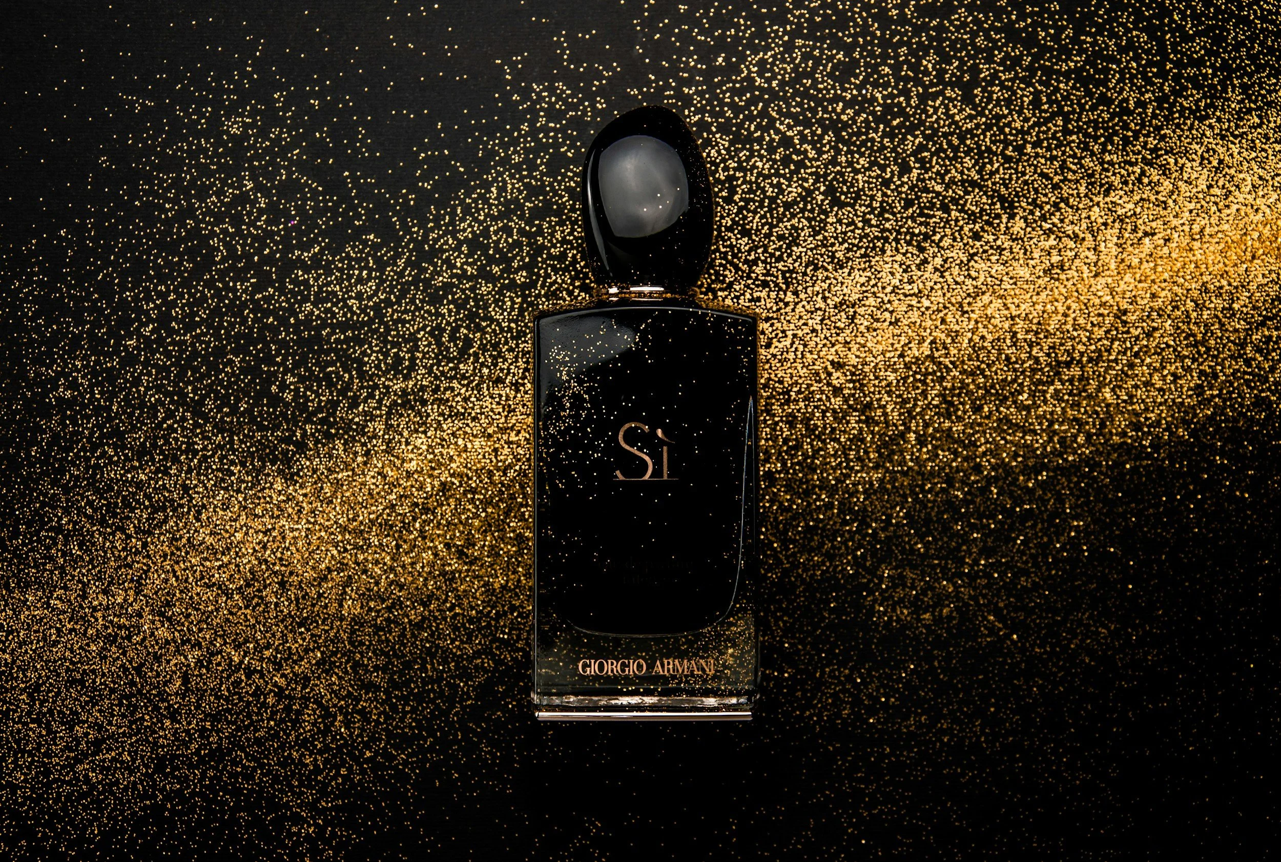 Frasco de perfume Giorgio Armani Sí, con fondo de polvo dorado y negro
