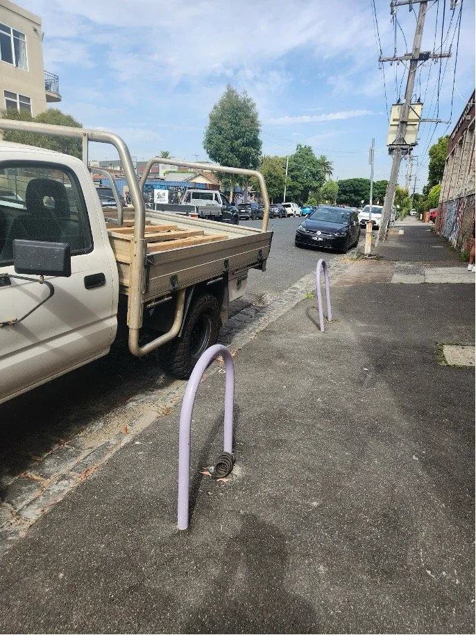 Two bike racks on a footpath outside Studio Take Care 