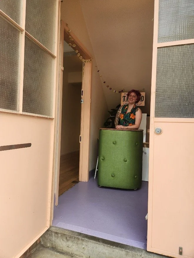 A person stands behind a podium in the front entryway of Studio Take Care