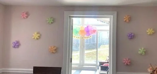 Decorated wall with colorful balloon flowers and a birthday banner.