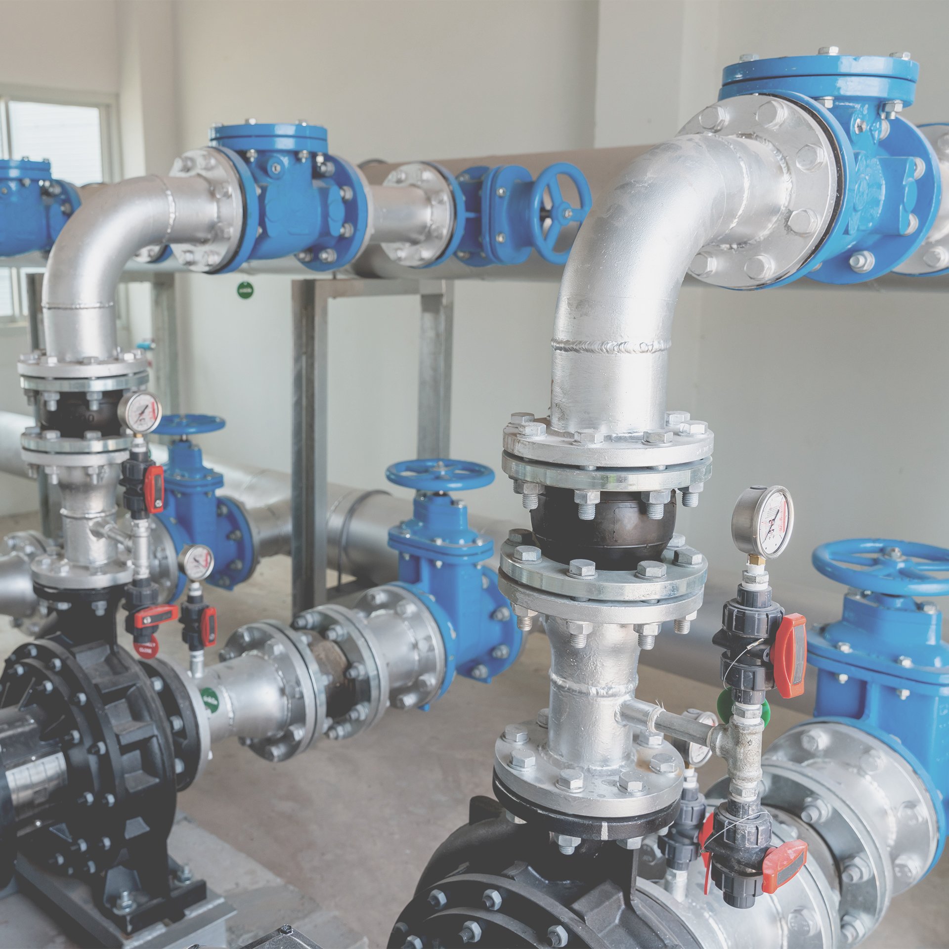 Industrial pipe system with blue valves and pressure gauges.