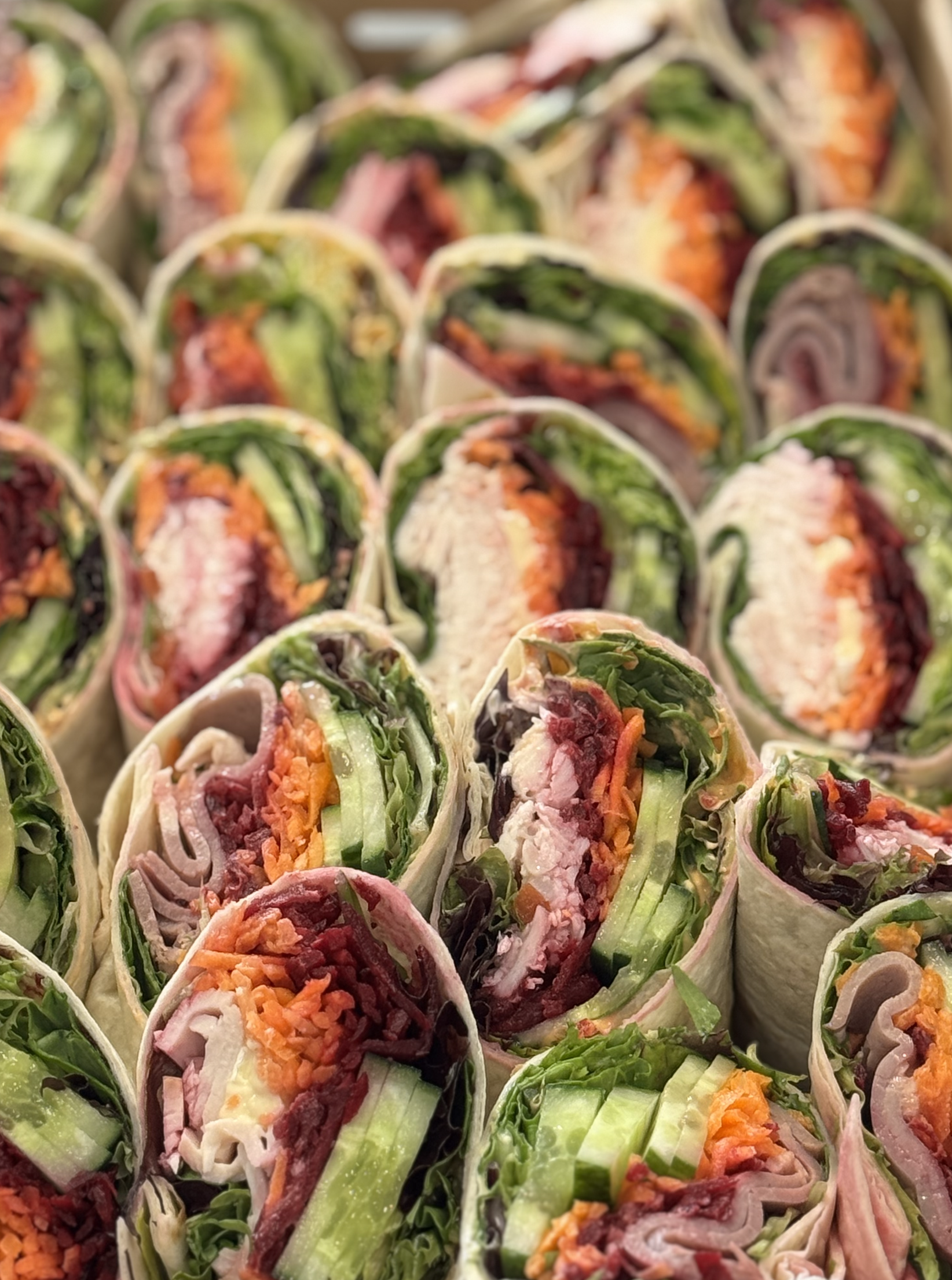 Close-up of assorted wraps filled with vegetables and meats.