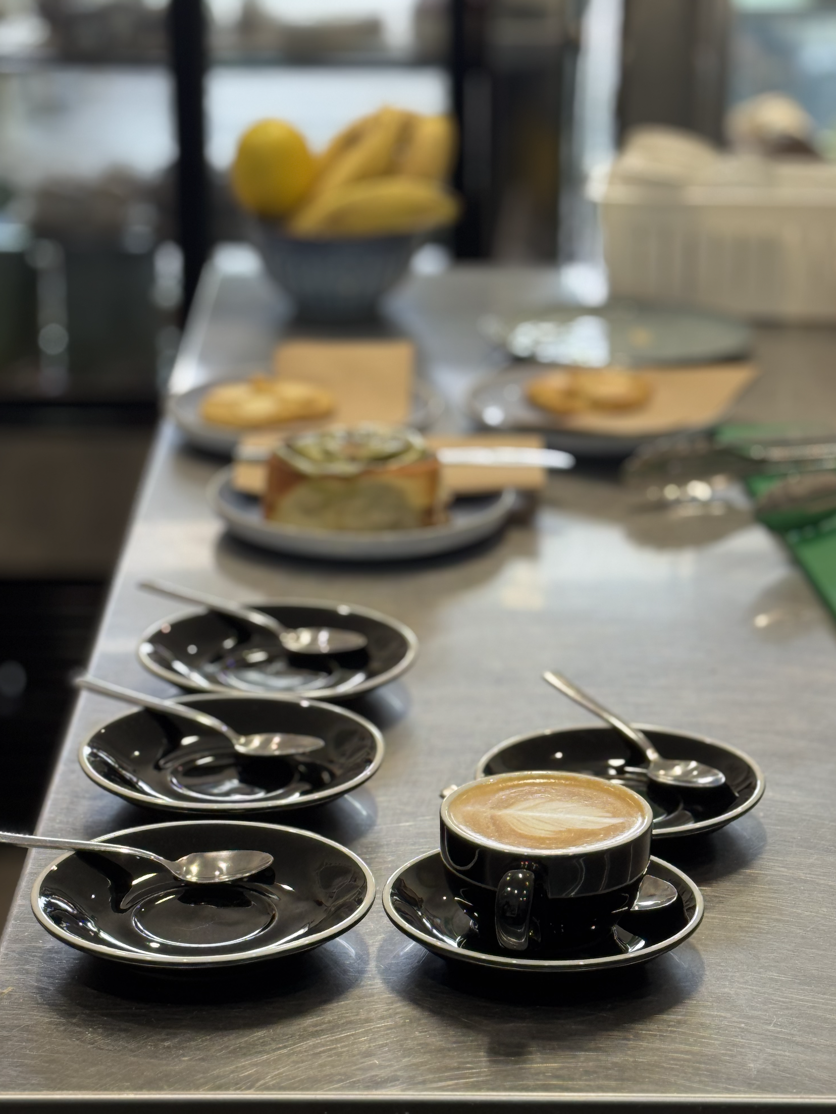 Multiple cups of coffee with saucers on a metal table in a cafe or restaurant.