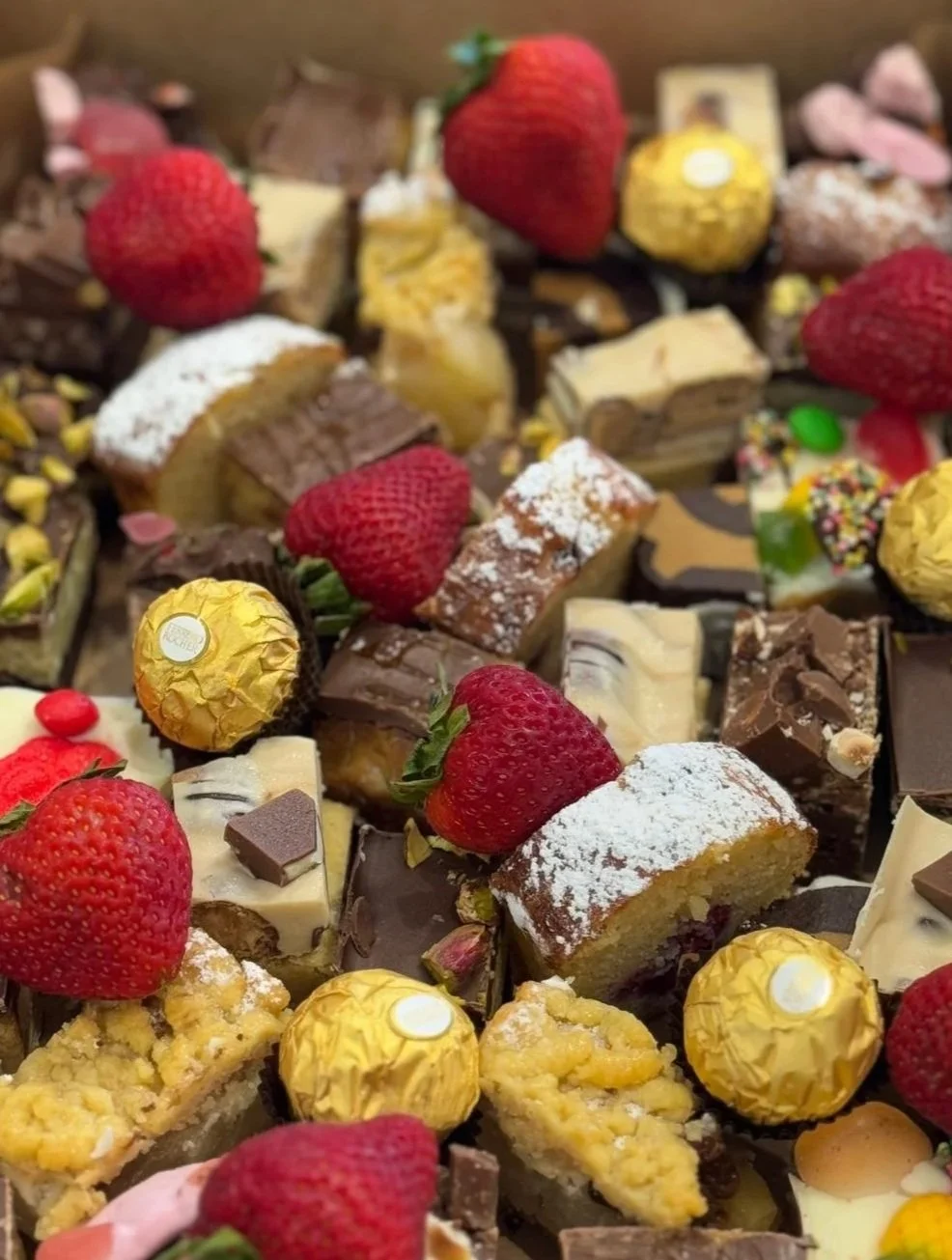 Assorted chocolates, strawberries, and candies arranged together.