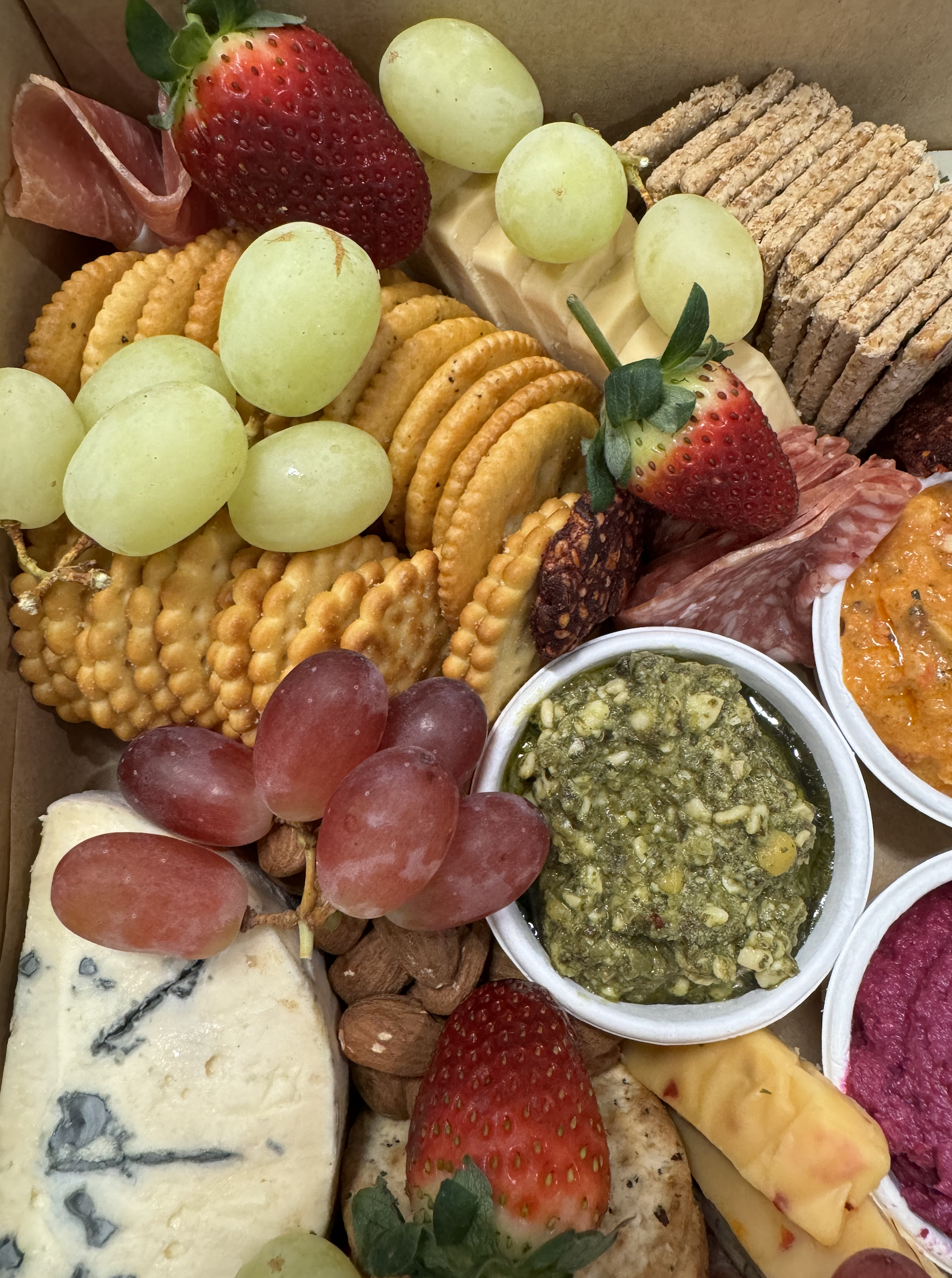 Assorted cheeses, grapes, strawberries, crackers, and charcuterie items on a platter.
