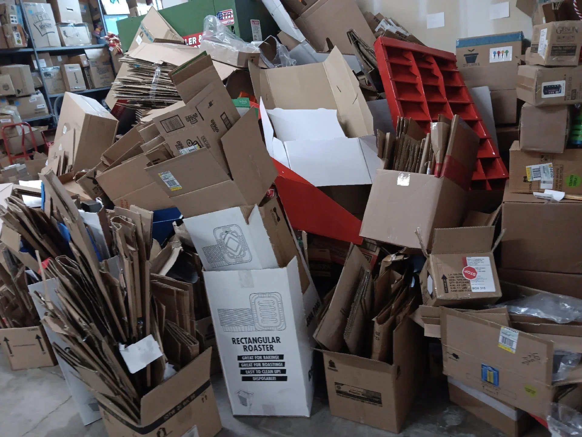 Pile of flattened cardboard boxes, some open and others stacked, in a storage or warehouse setting.