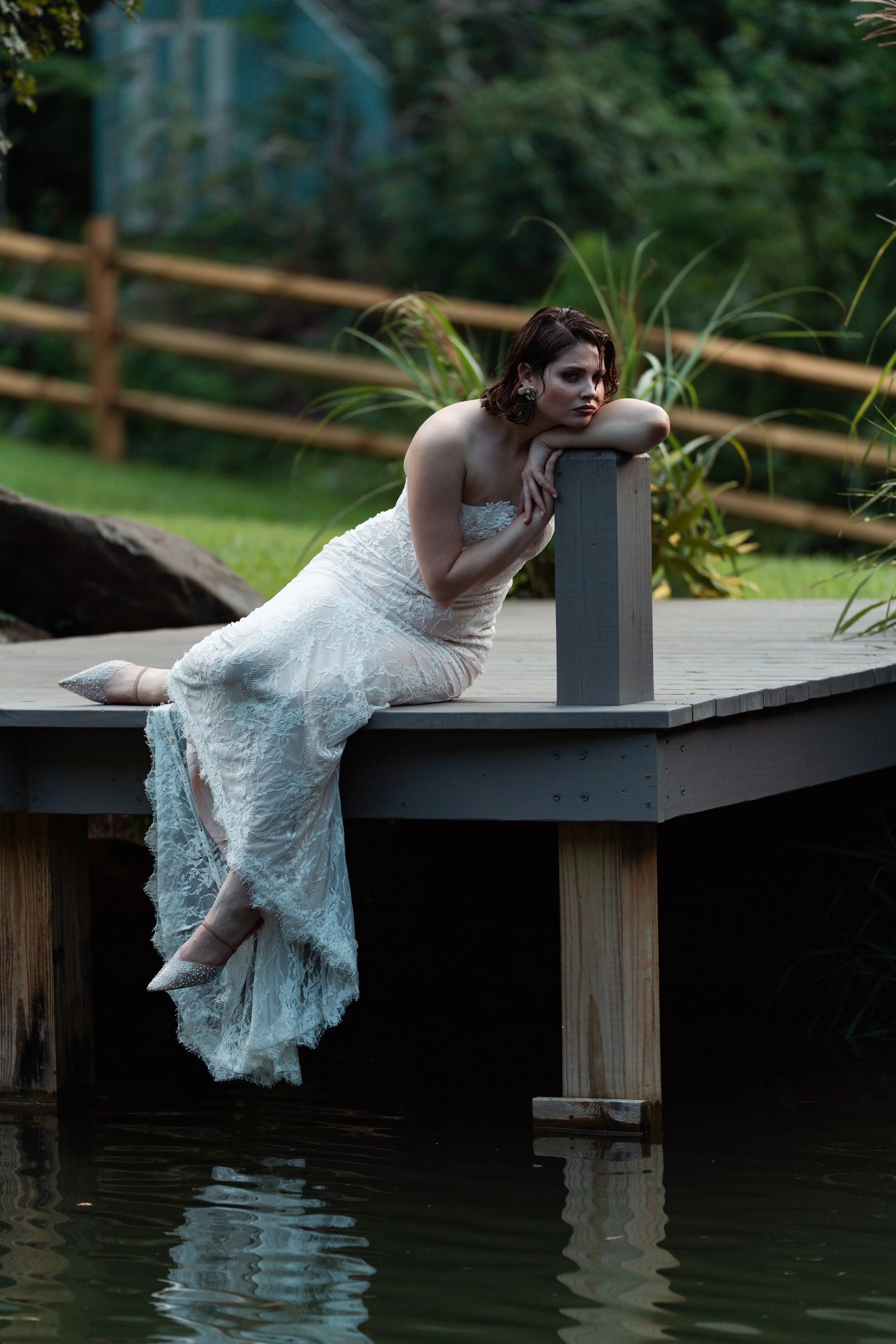 Bride sitting on the dock overlooking the pond at Caya Azul, a private mountain retreat and wedding destination near Asheville.