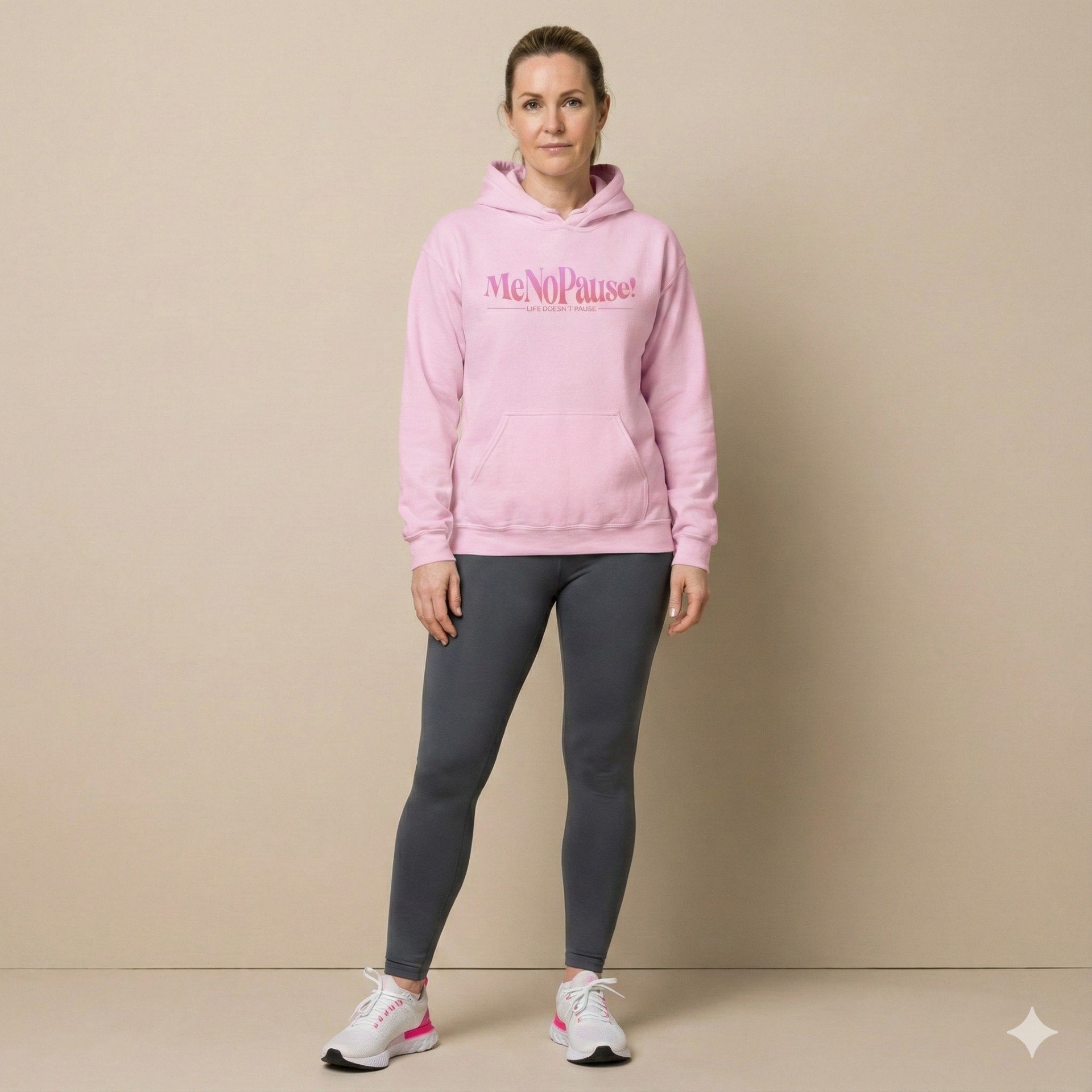 Woman wearing light pink unisex MeNoPause!™ Empowerment Hoodie with centered pink logo.