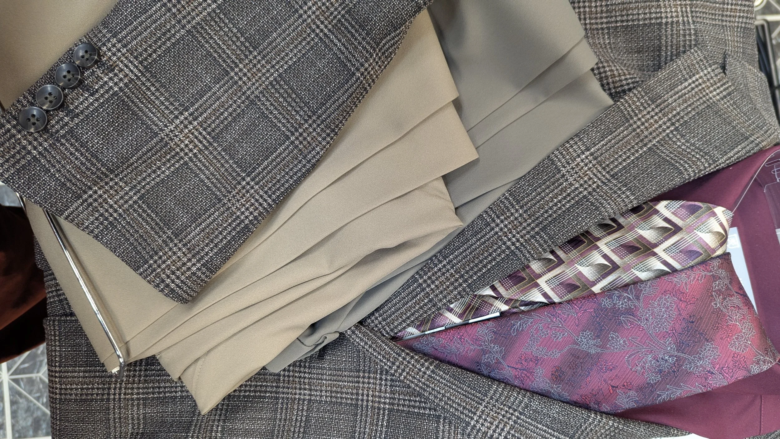 Black, Tan and White sports coat with two different color of tan and grey dress pants and two colorful burgundy patterned ties.