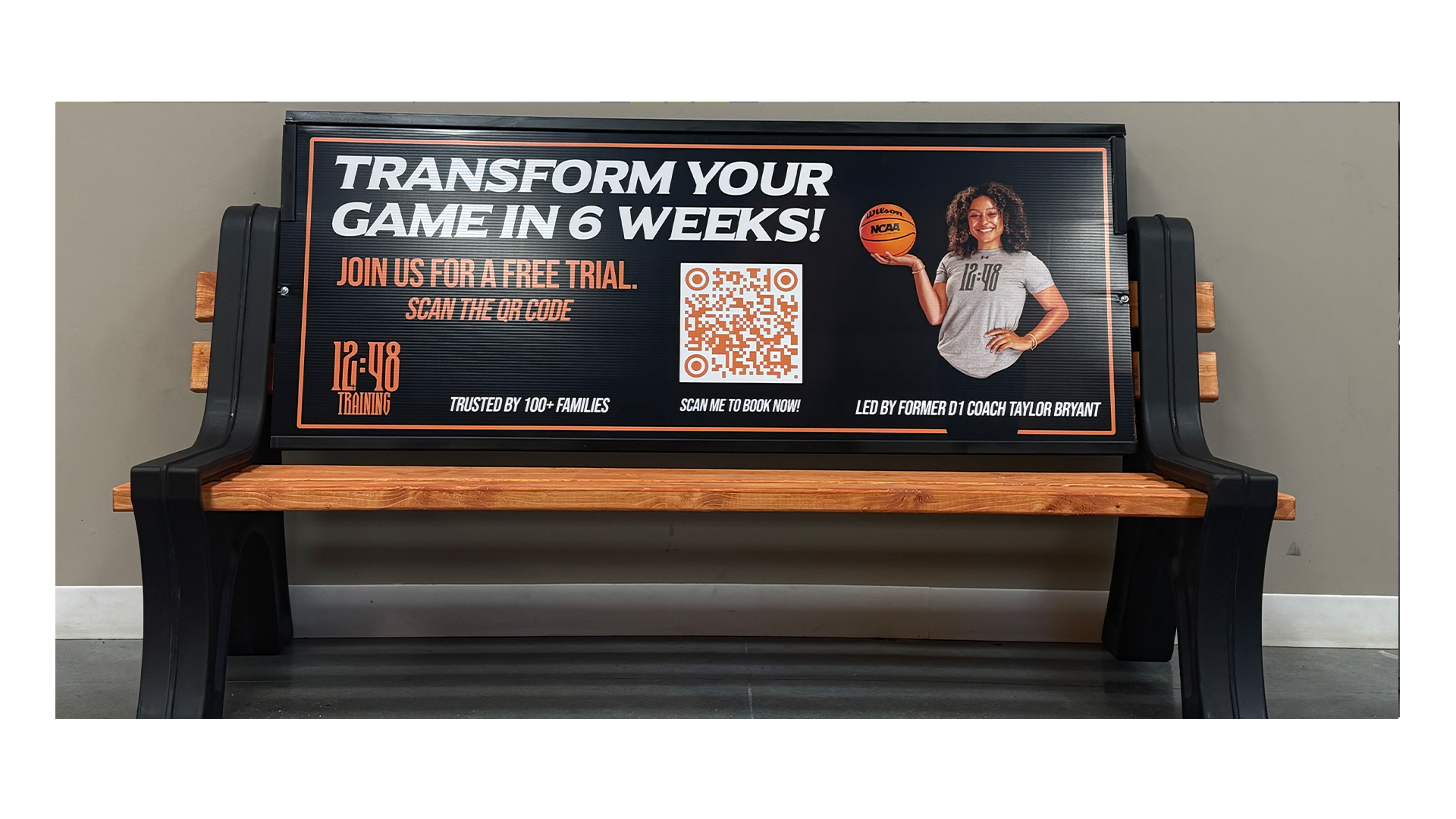 Bench billboard with text that's says Transform Your Game in 6 Weeks. Join us for a free trial. Scan the QR code. 12:48 Training. Trusted by 100 + families. Scan to book NOW! Led by Former D1 Coach Taylor Bryant