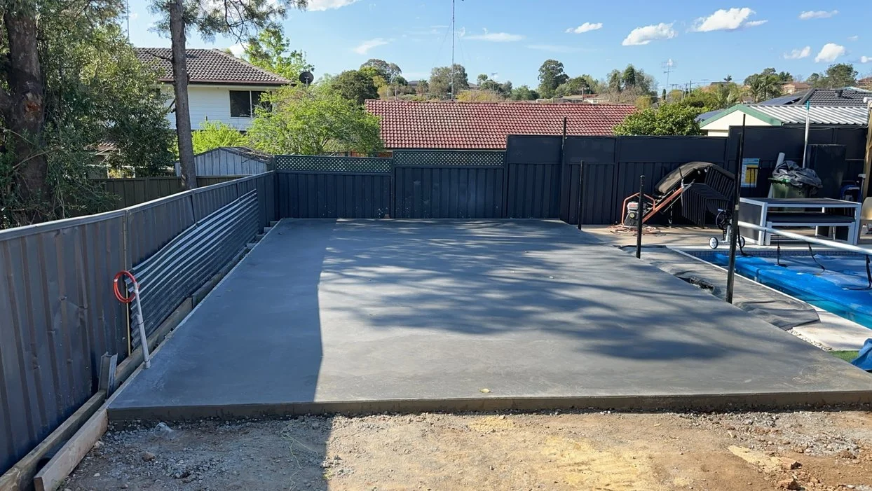 Freshly poured concrete slab in backyard adjacent to pool