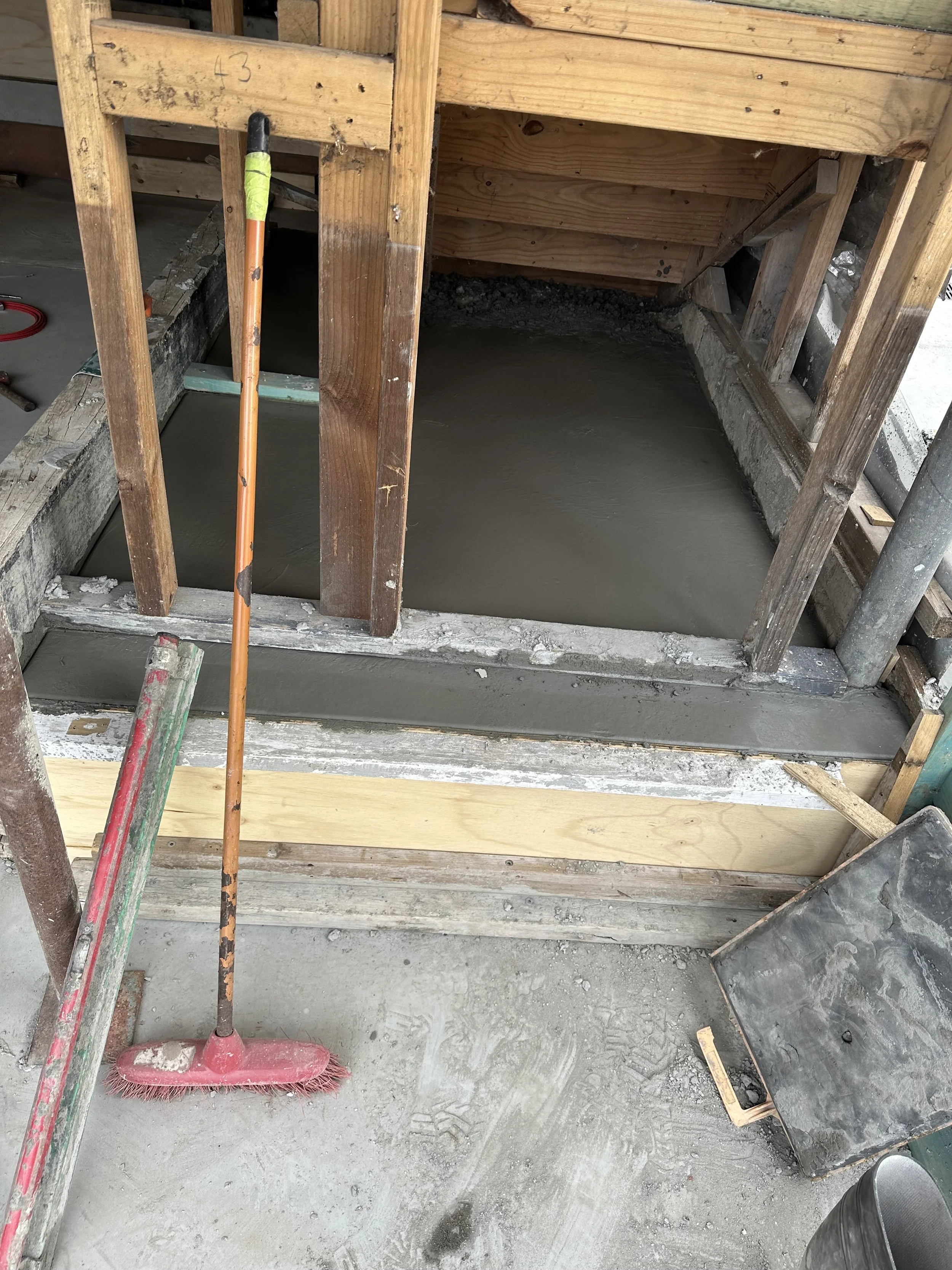 Concrete being poured into a wooden framing structure at a construction site.
