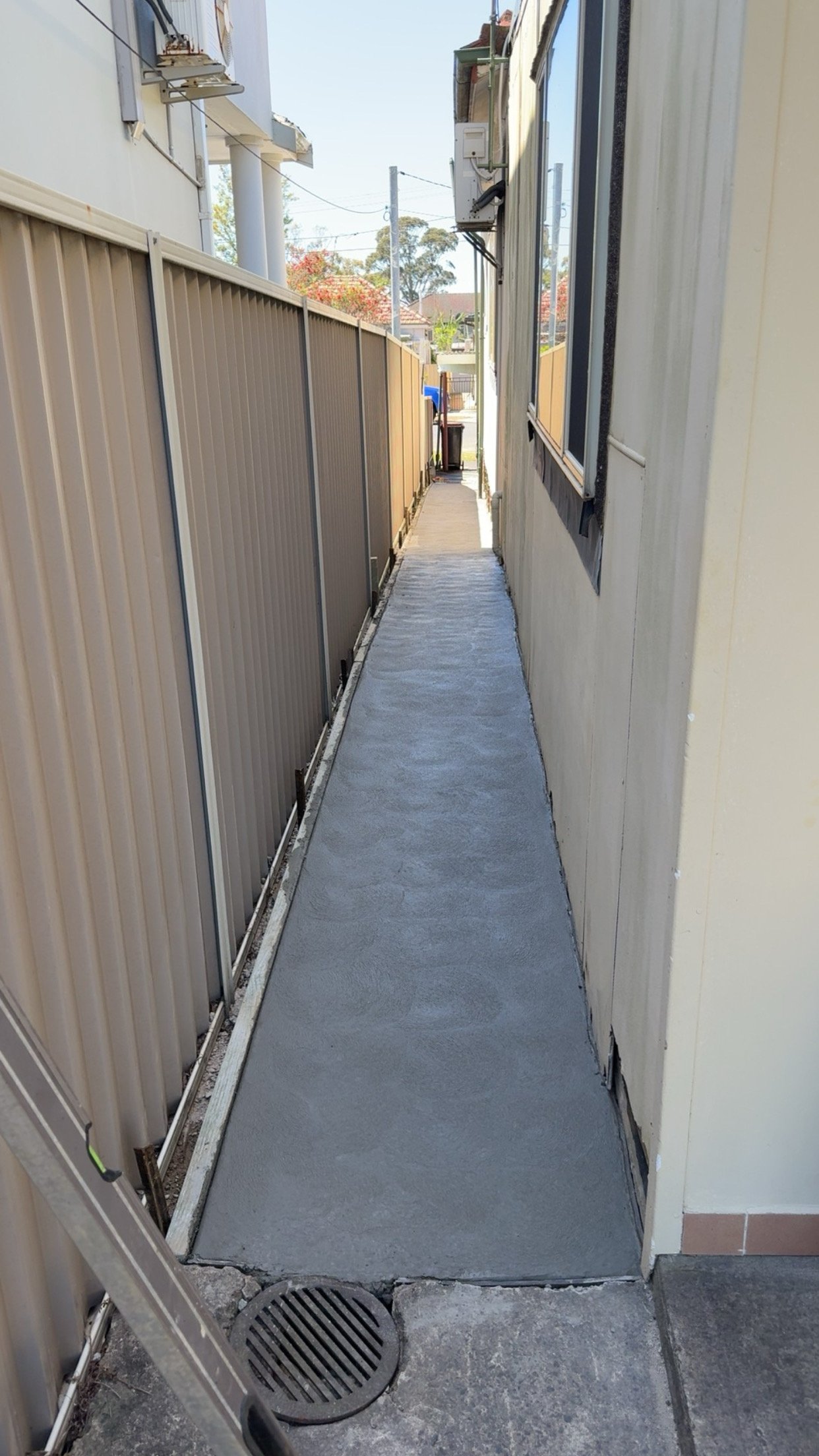 Narrow outdoor pathway with a freshly poured concrete walkway