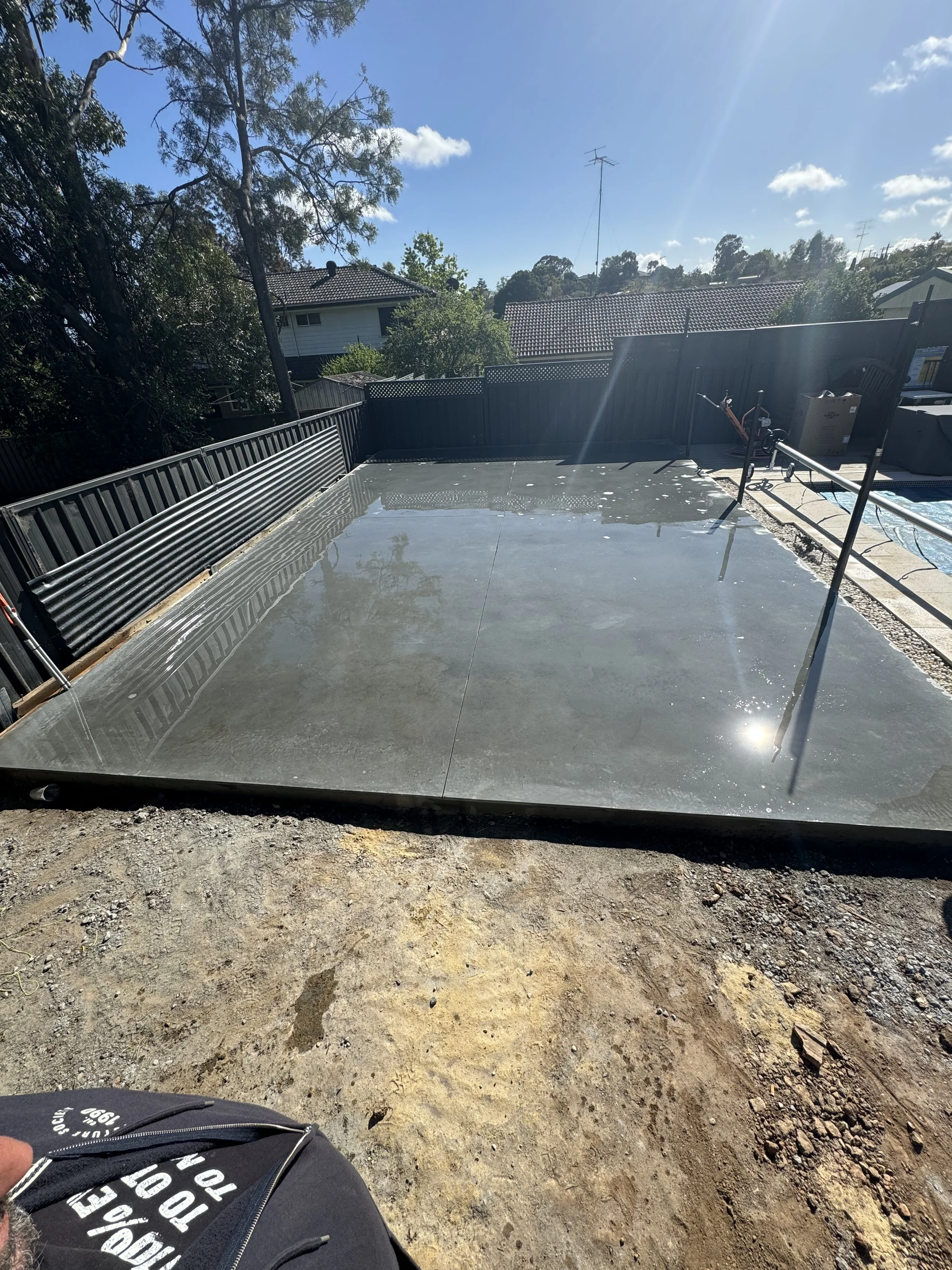 A newly poured concrete slab in a backyard
