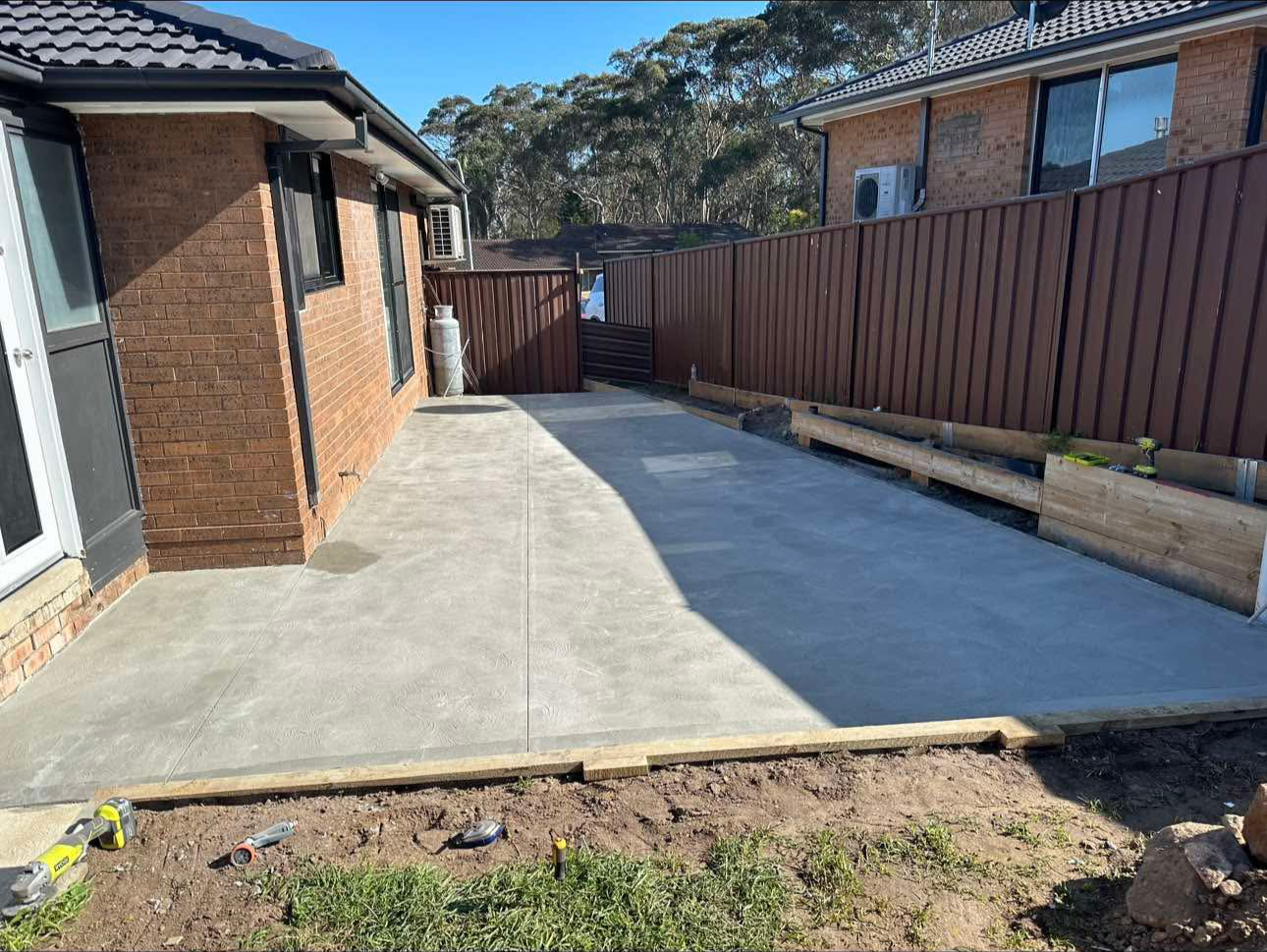 Newly poured concrete patio in backyard of brick house