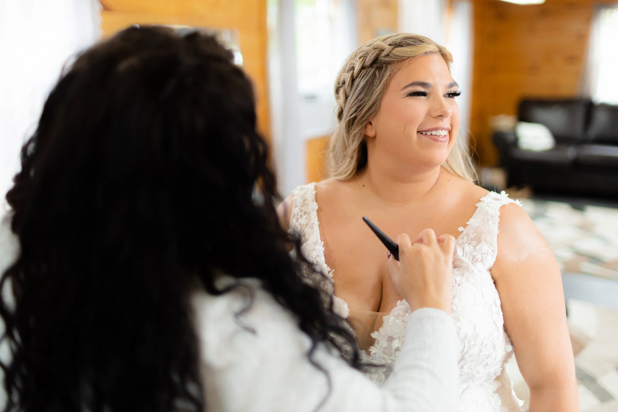 makeup artist applying body makeup to brides chest as she smiles