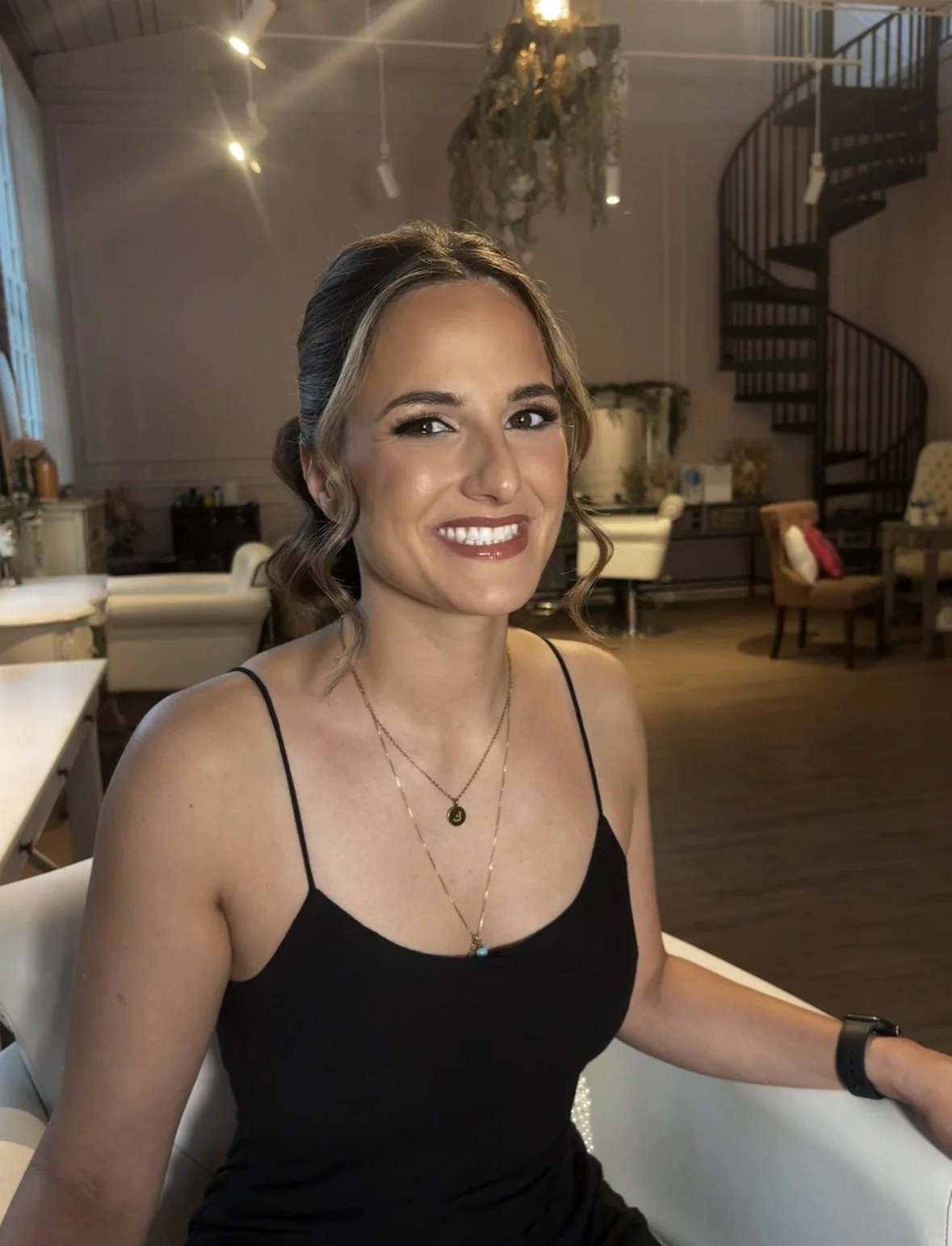 Brown haired makeup model with hair in a ponytail wearing a black tank top 