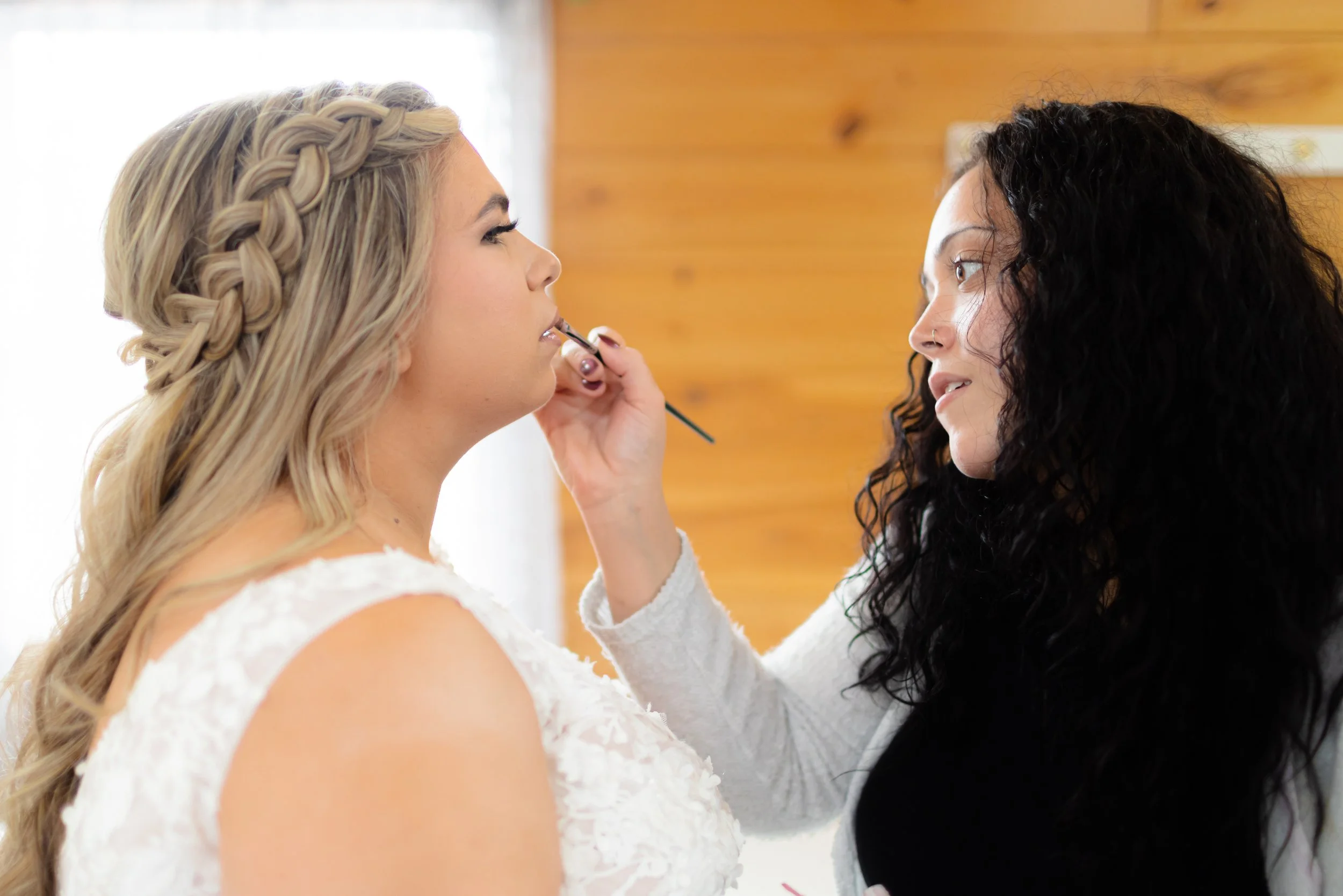 Makeup artist applying lip color to a Bride with a makeup brush