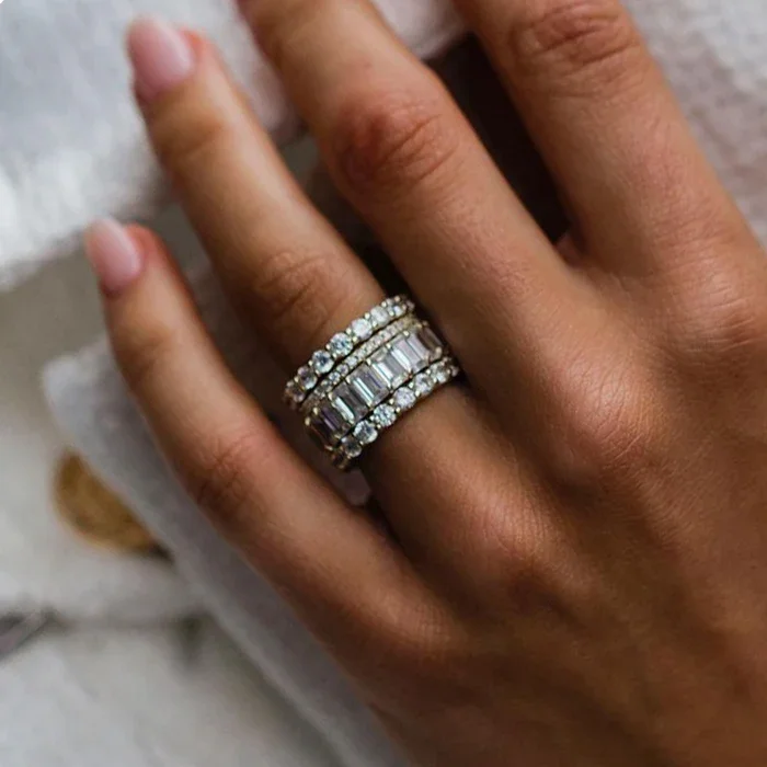 Close-up of a person's hand wearing multiple diamond rings on the ring finger.