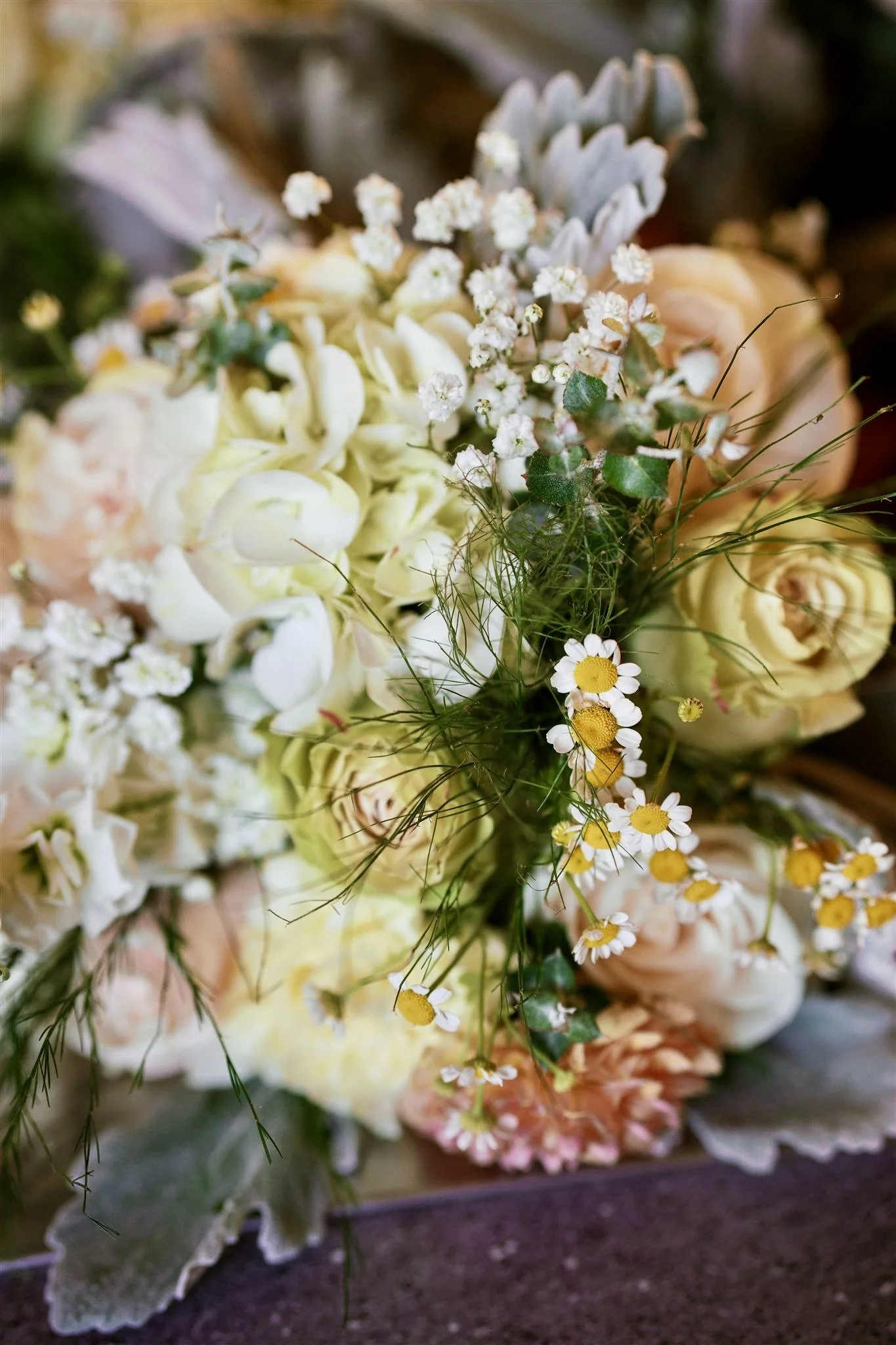 A bouquet of various flowers including white roses, daisies, small white blossoms, and greenery.