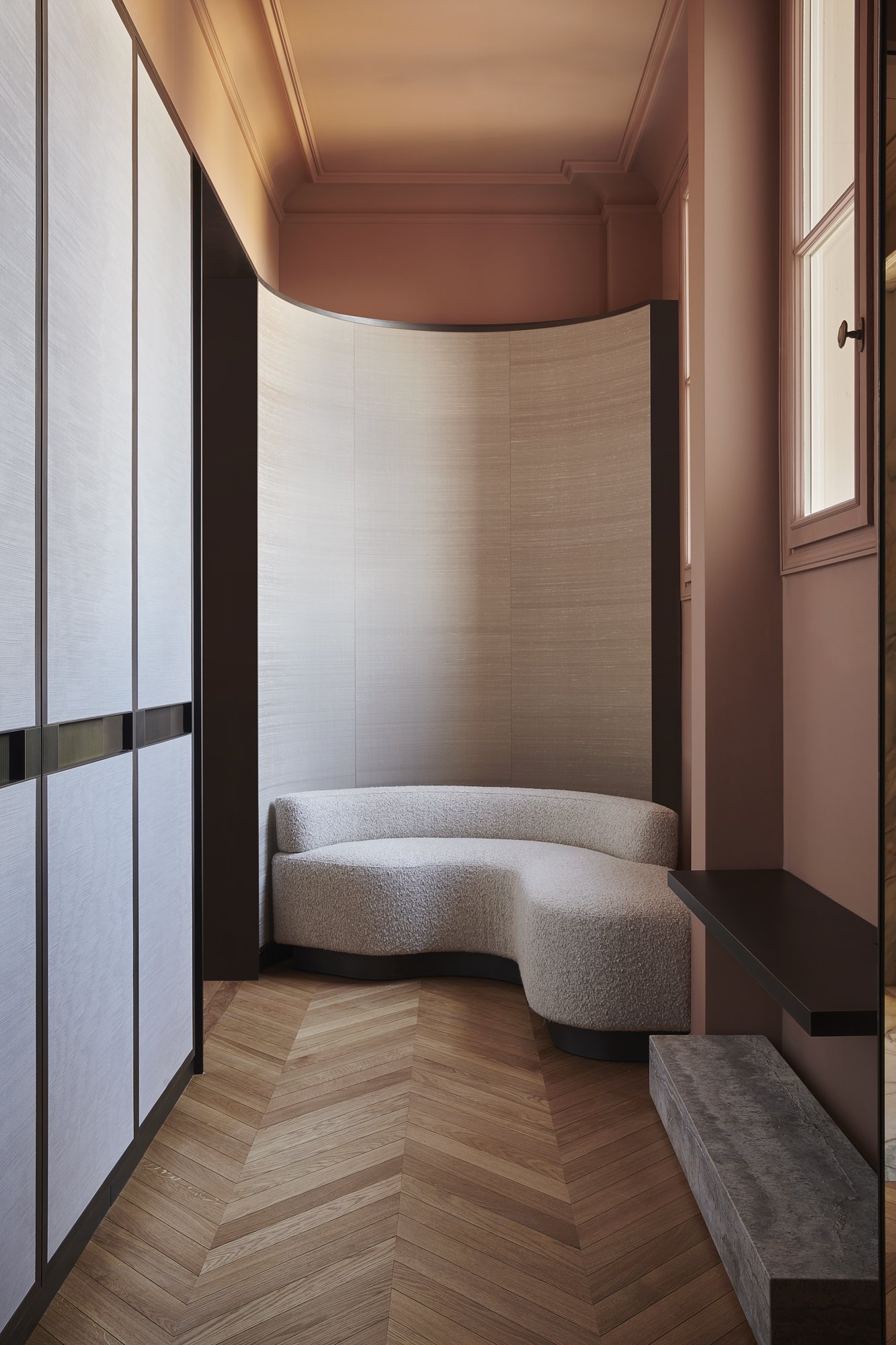 banquette sur mesure avec panneaux courbes gainés de tissu, placards gainés de tissu et  poignées en laiton patiné fabriqués par l'ébéniste agenceur Lamellux