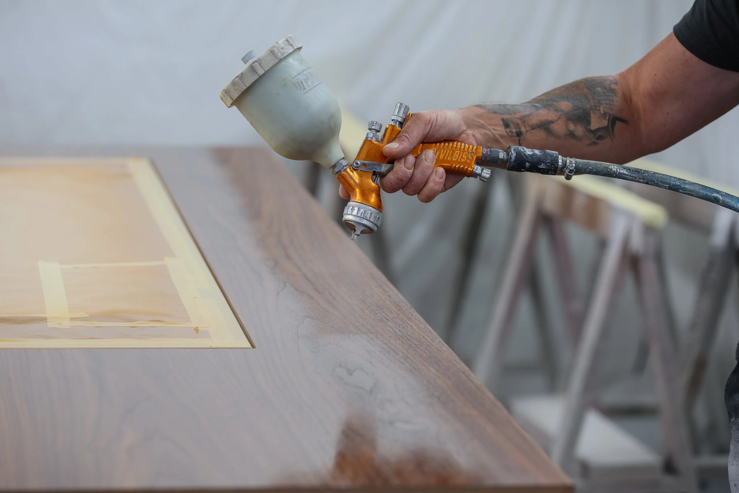 ébéniste agenceur vernisseur passe le vernis de finition en cabine de finition sur du bois dans l'atelier Lamellux