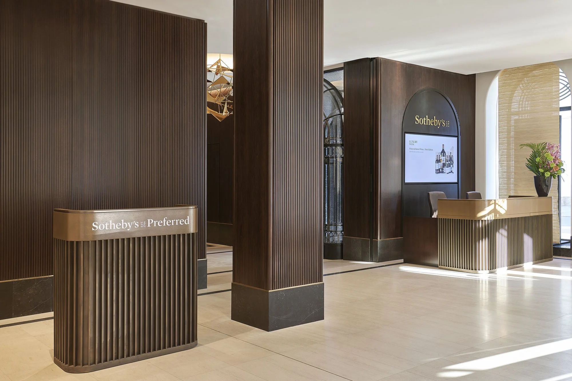 Agencement d'un projet tertiaire avec habillage en bois du hall d'entrée et comptoirs d'accueil en laiton patiné par Lamellux