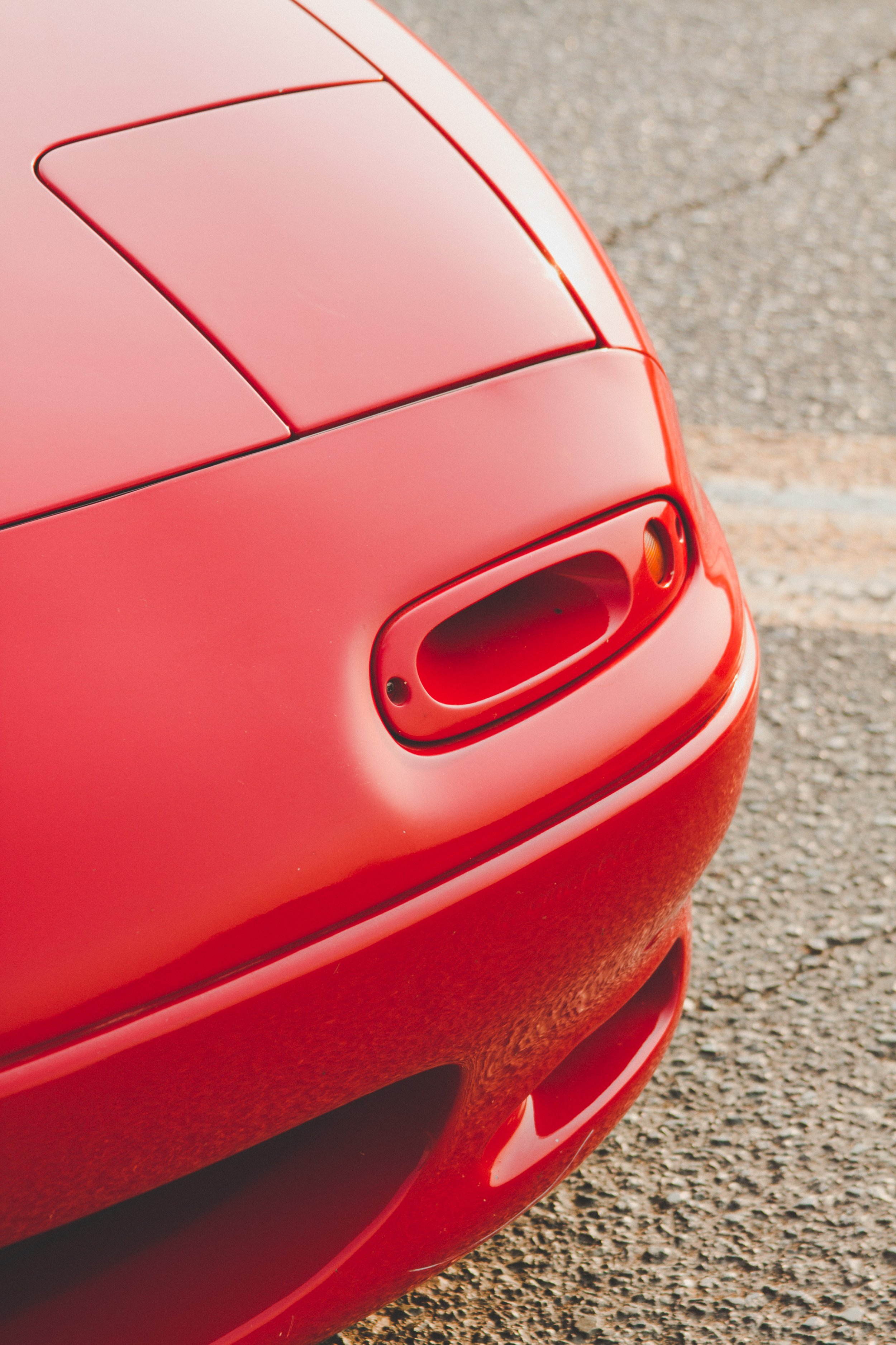 Close-up of the rear part of a red sports car, showing the trunk and rear bumper on a paved surface.