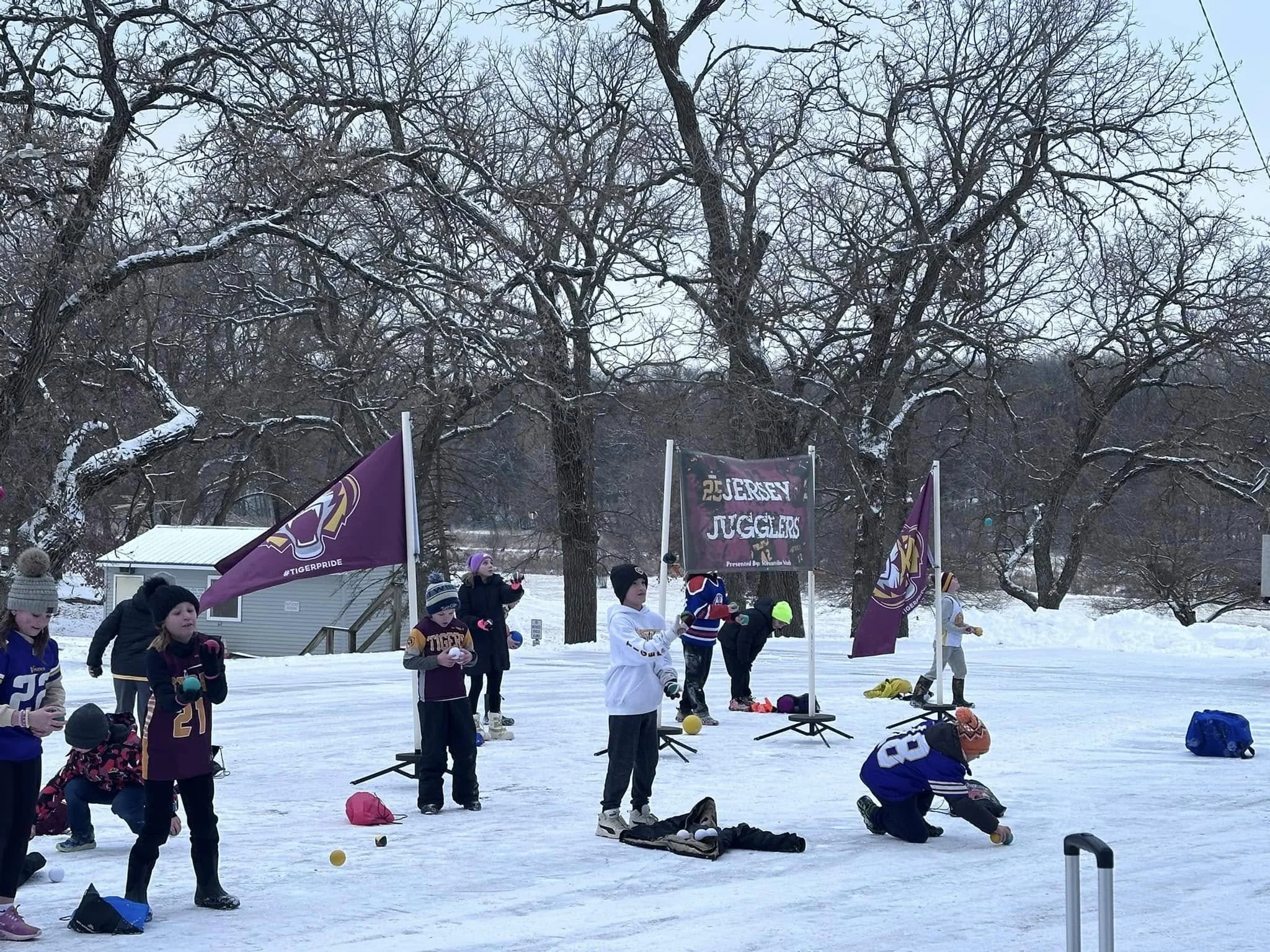 Children unloading snowballs and preparing to throw at a winter outdoor event in a snowy park.