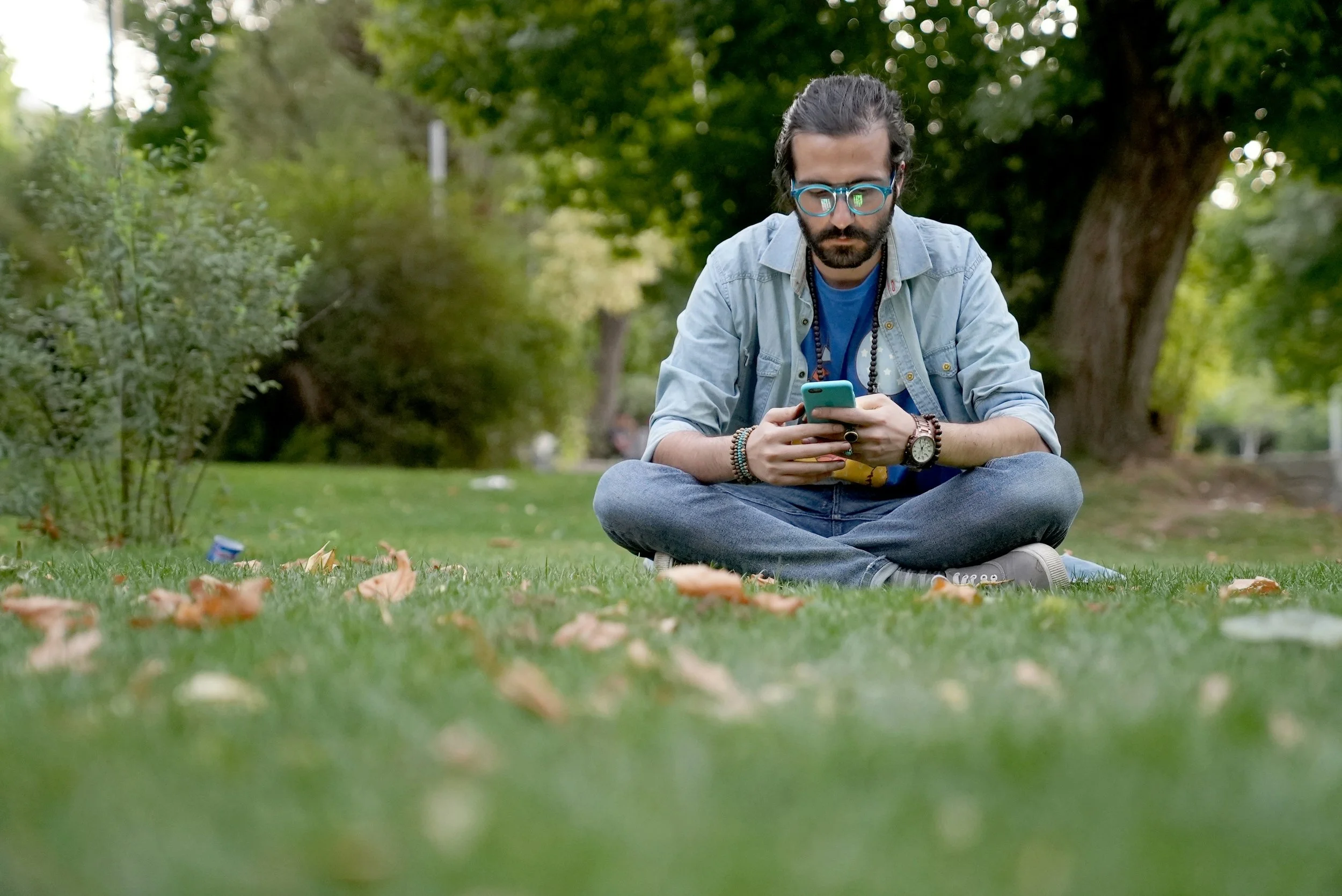 thoughtful young man sitting in park and using mindfulness apps