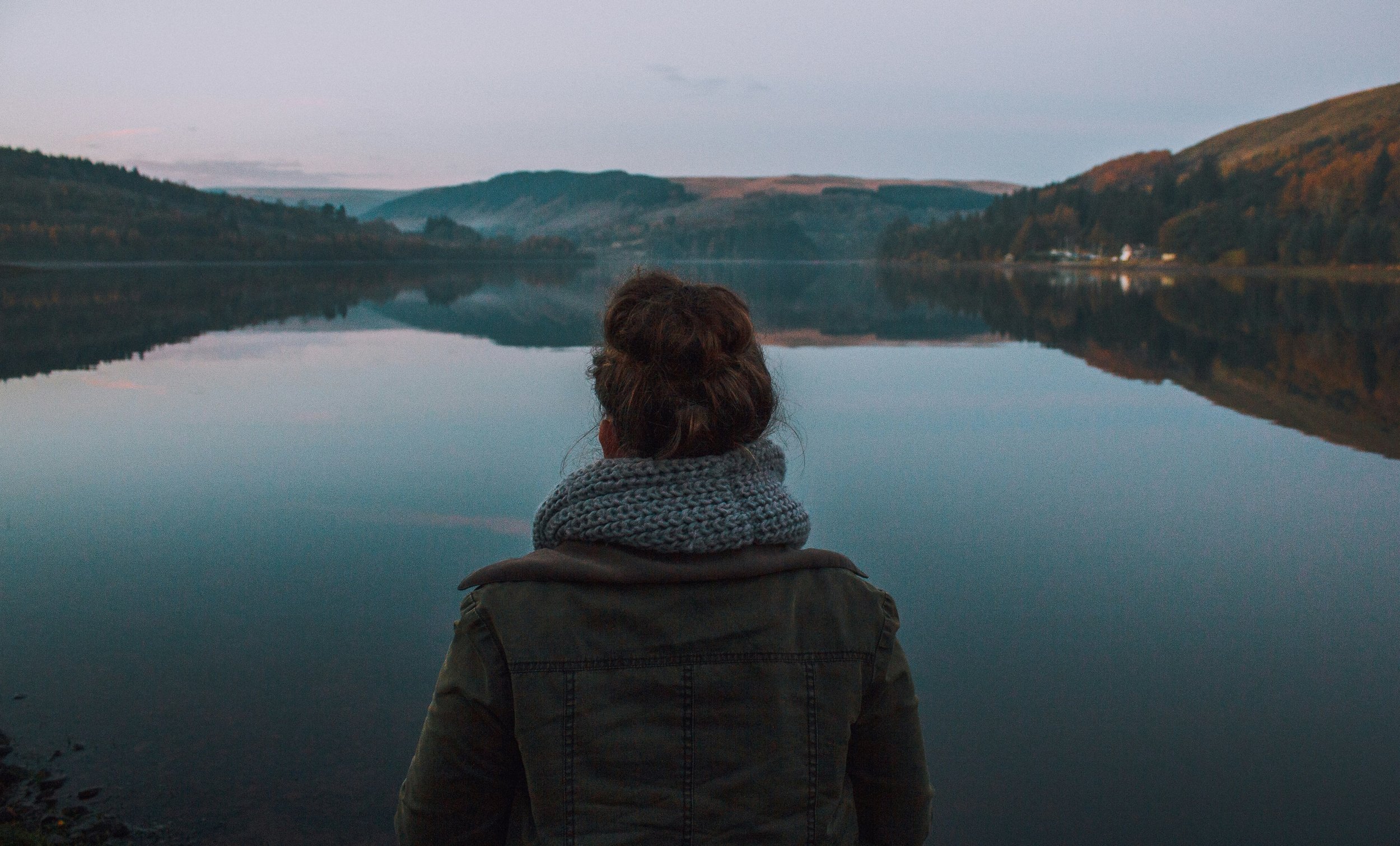 young woman being mindful staring into a still lake