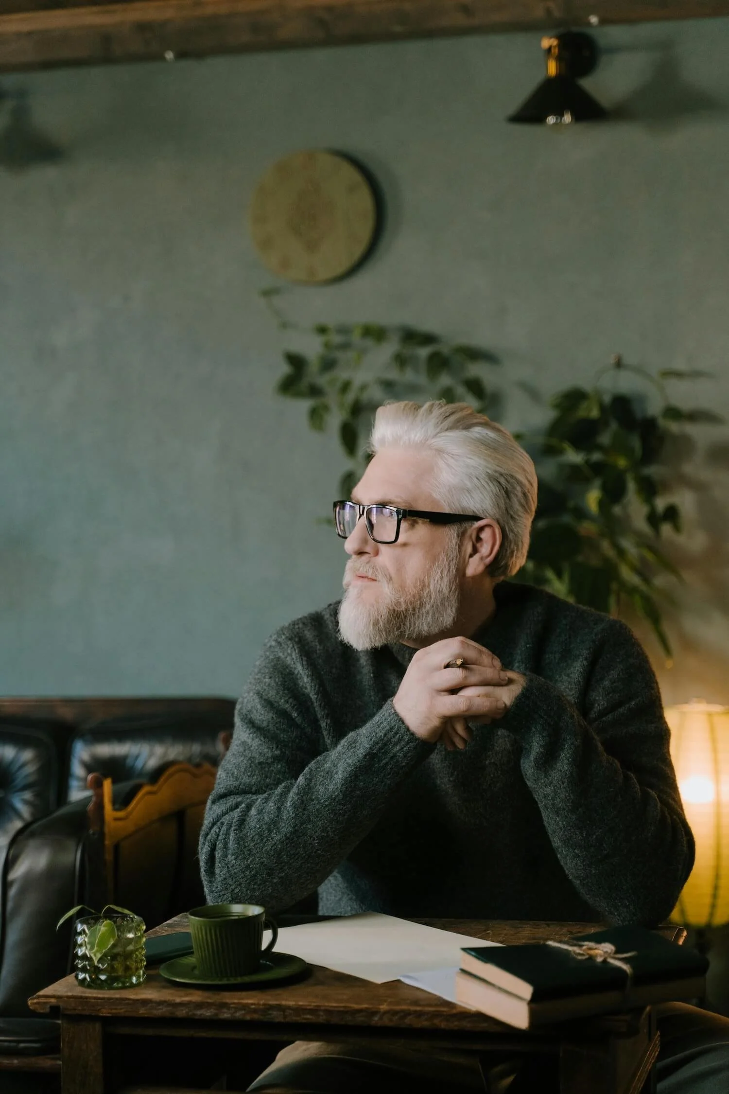 Older man with glasses and a grey beard sitting in quiet reflection, men's help groups Blue Mountains