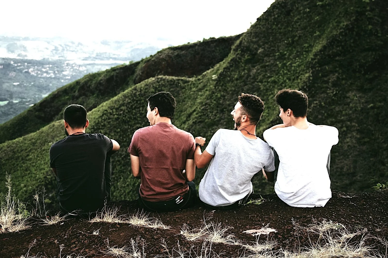 four young men on mountqins having fun looking into nature