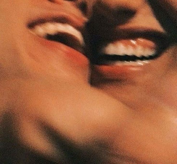 Close-up of two people smiling and appearing to kiss each other.