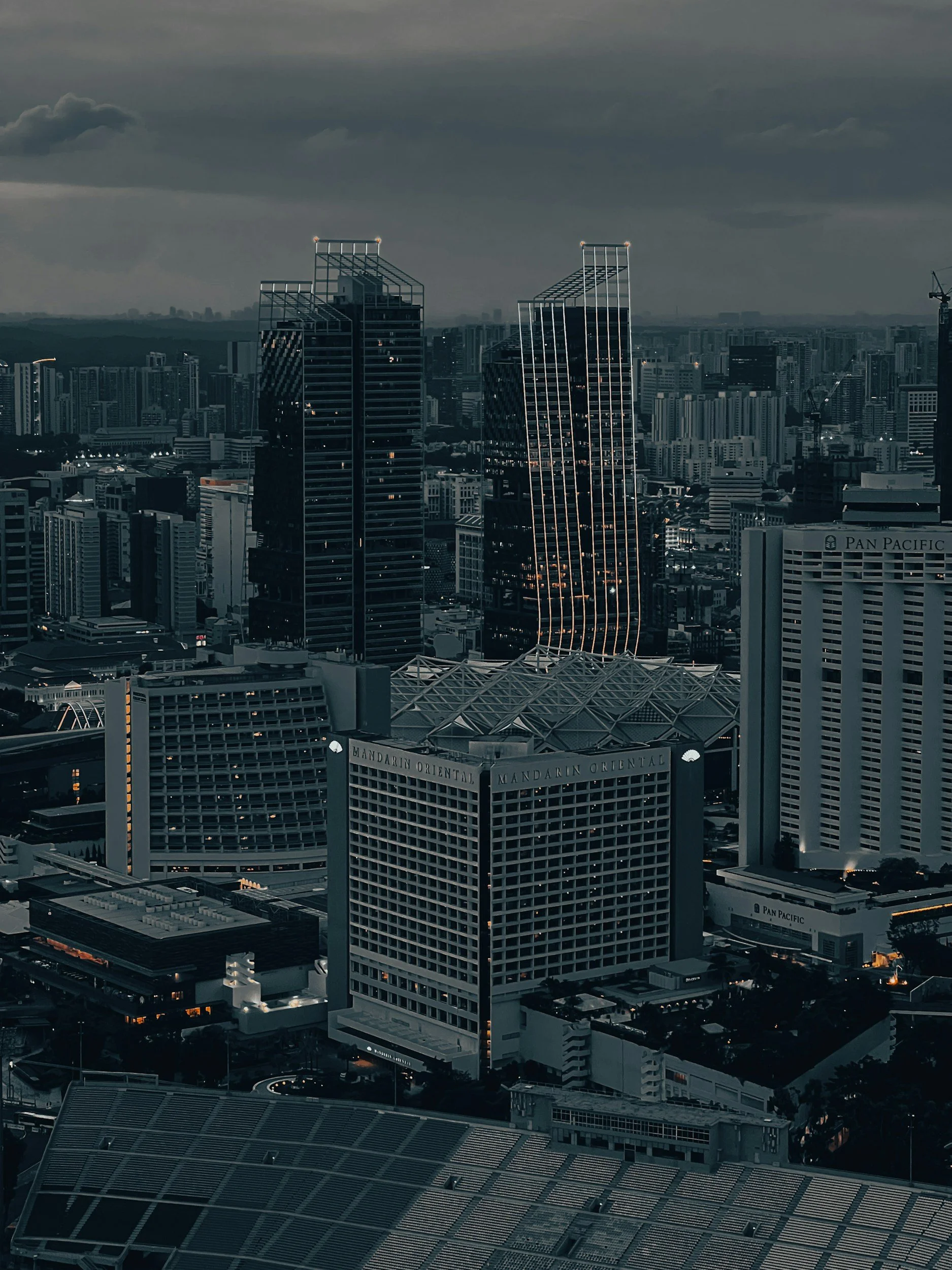 Nighttime cityscape with modern high-rise buildings and a cloudy sky.