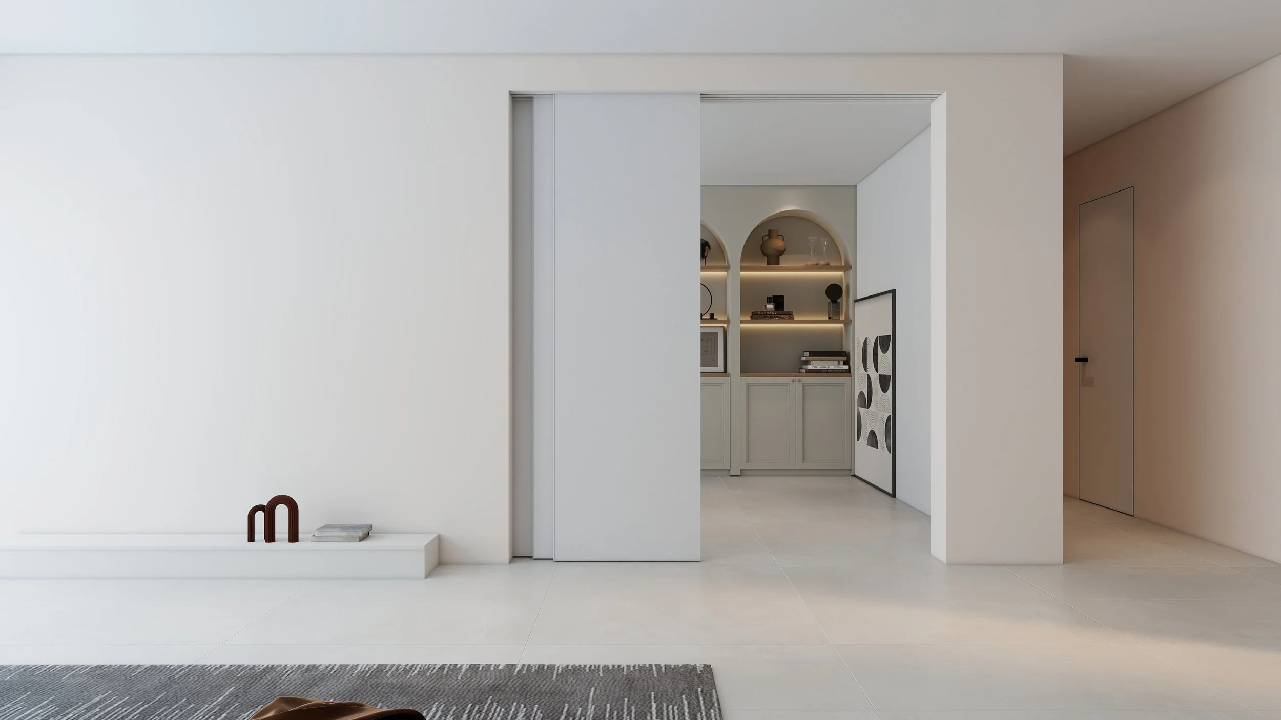 Minimalist living space with white walls, a sliding door, built-in shelves with decor, and a gray and white area rug.