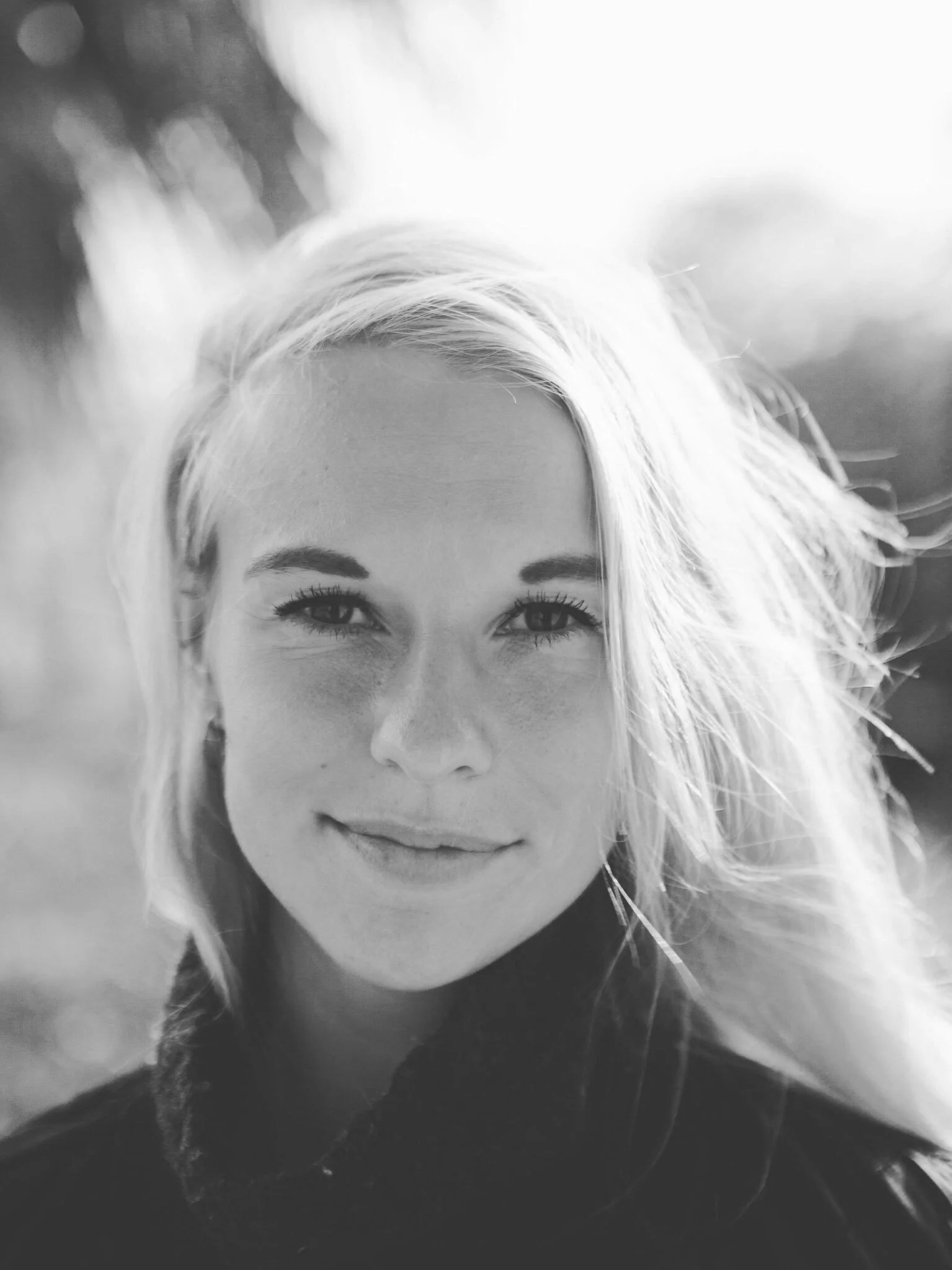 Sort-hvidt portræt af en kvinde med blondt hår og smilende ansigt