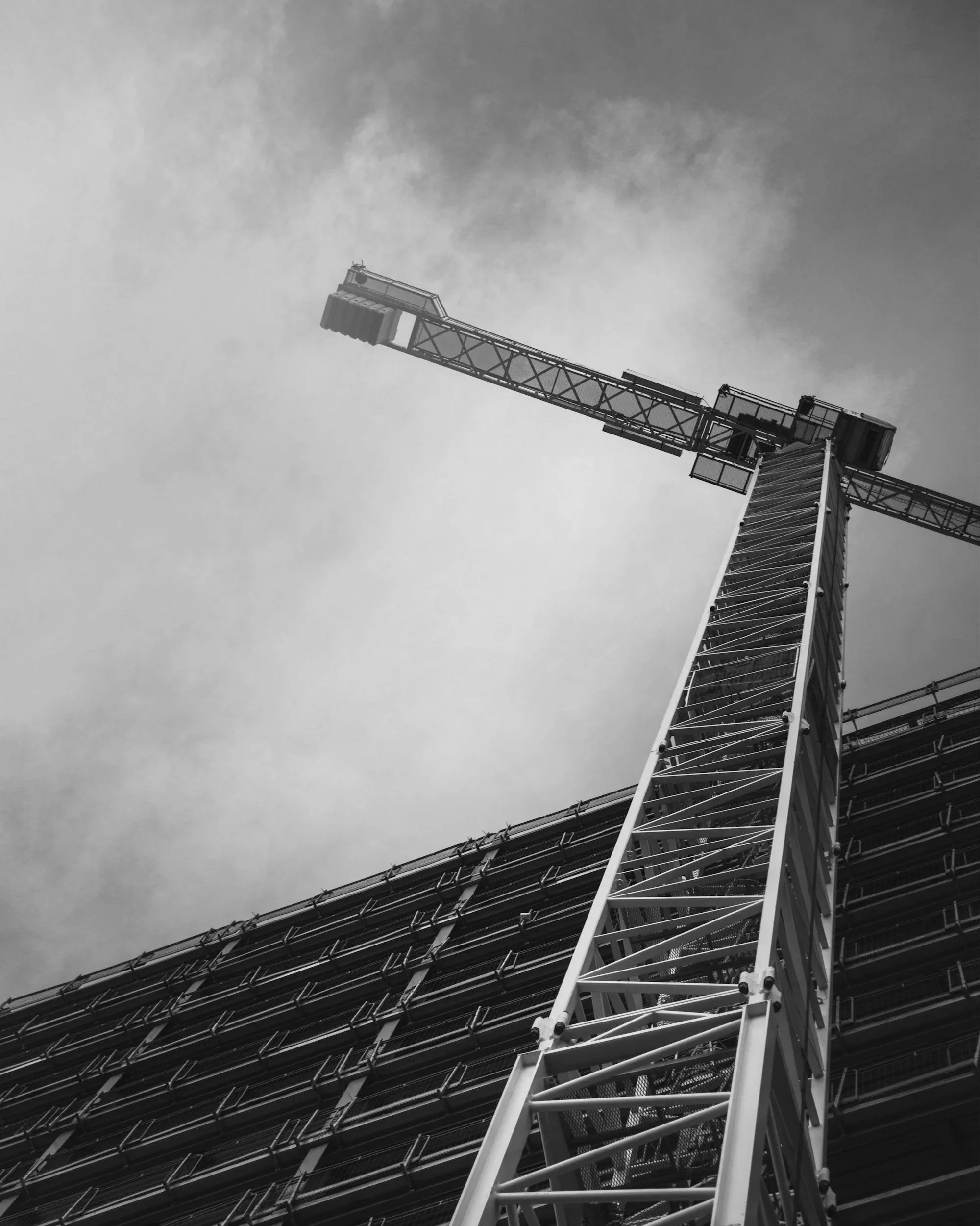 Costruzione di un edificio con gru in alto, vista in bianco e nero