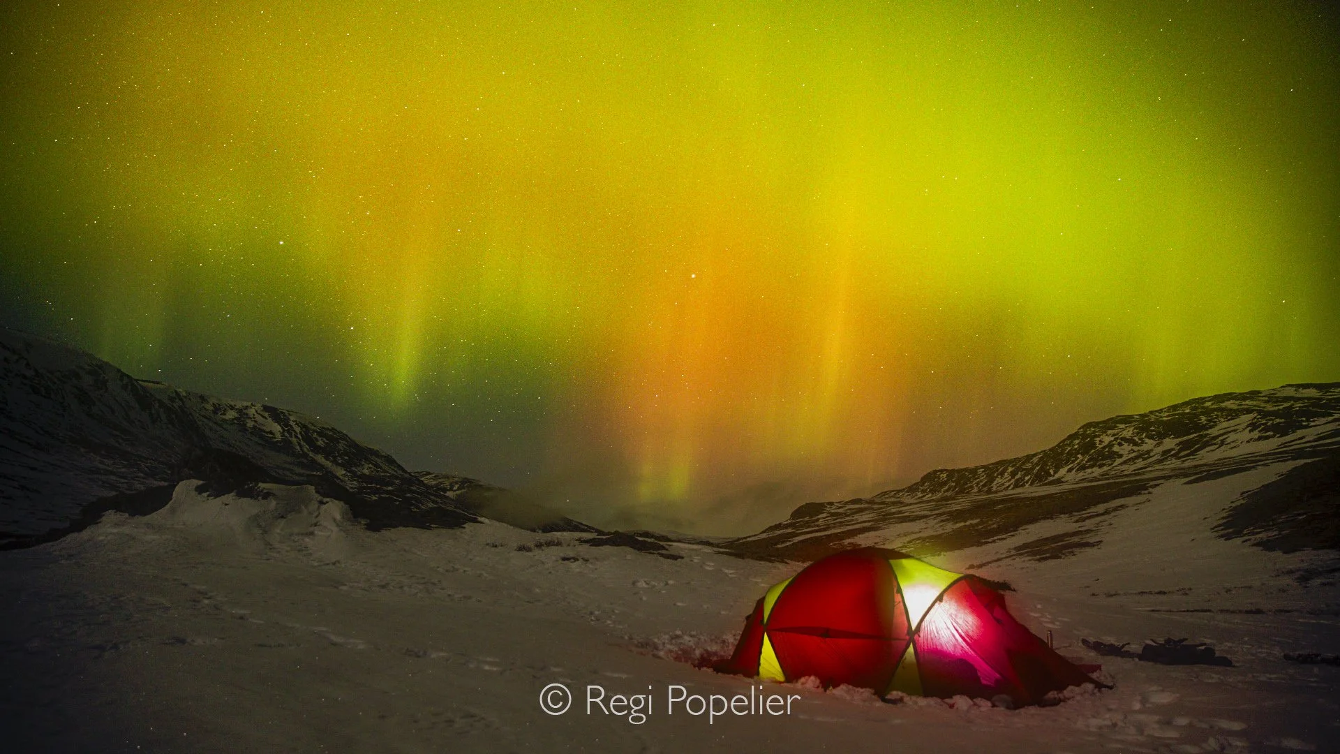 NORWAY061 - Alone in the frozen wilderness, I spent the night beneath shimmering curtains of green light. The illuminated tent became a quiet reminder of how small we are beneath the endless Arctic sky.