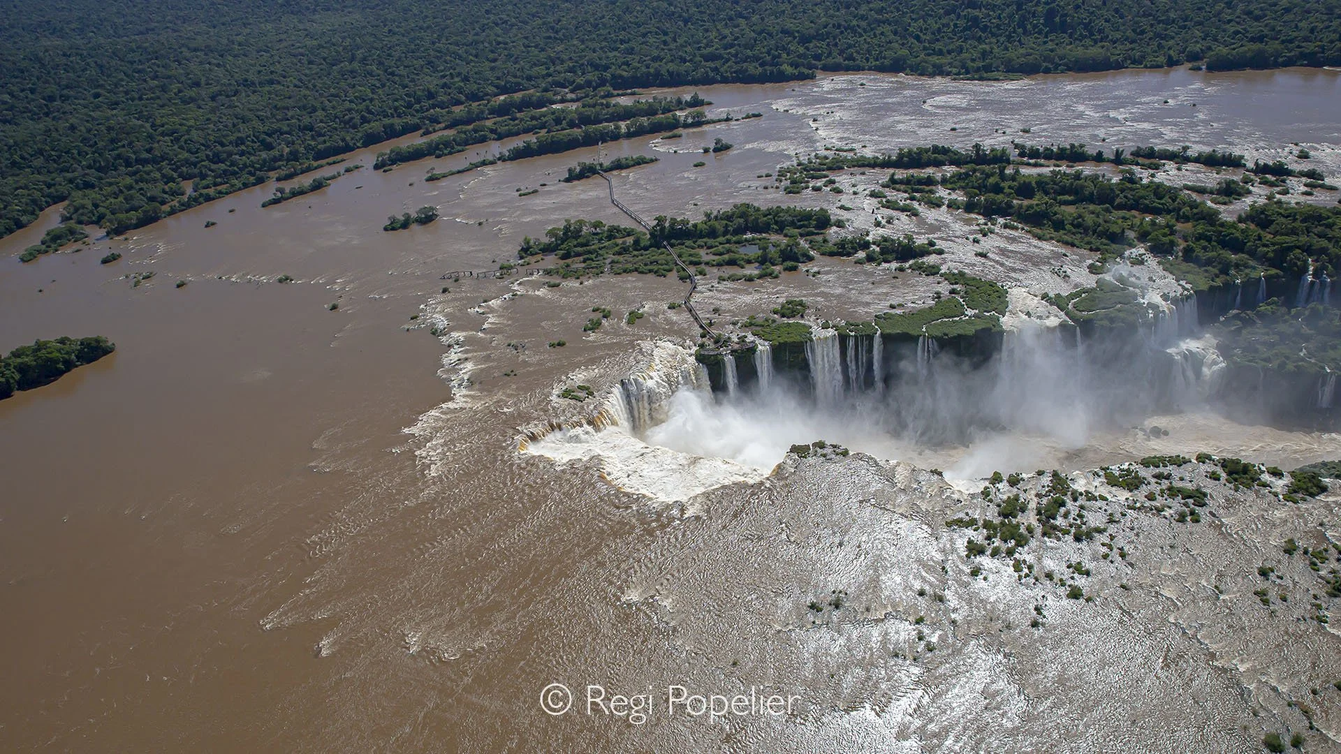 BRA003 - Helicopter perspective over Iguassu Falls reveals the true scale of this natural giant and endless cascades, swirling mist, and raw power carved into the landscape, seen from above.