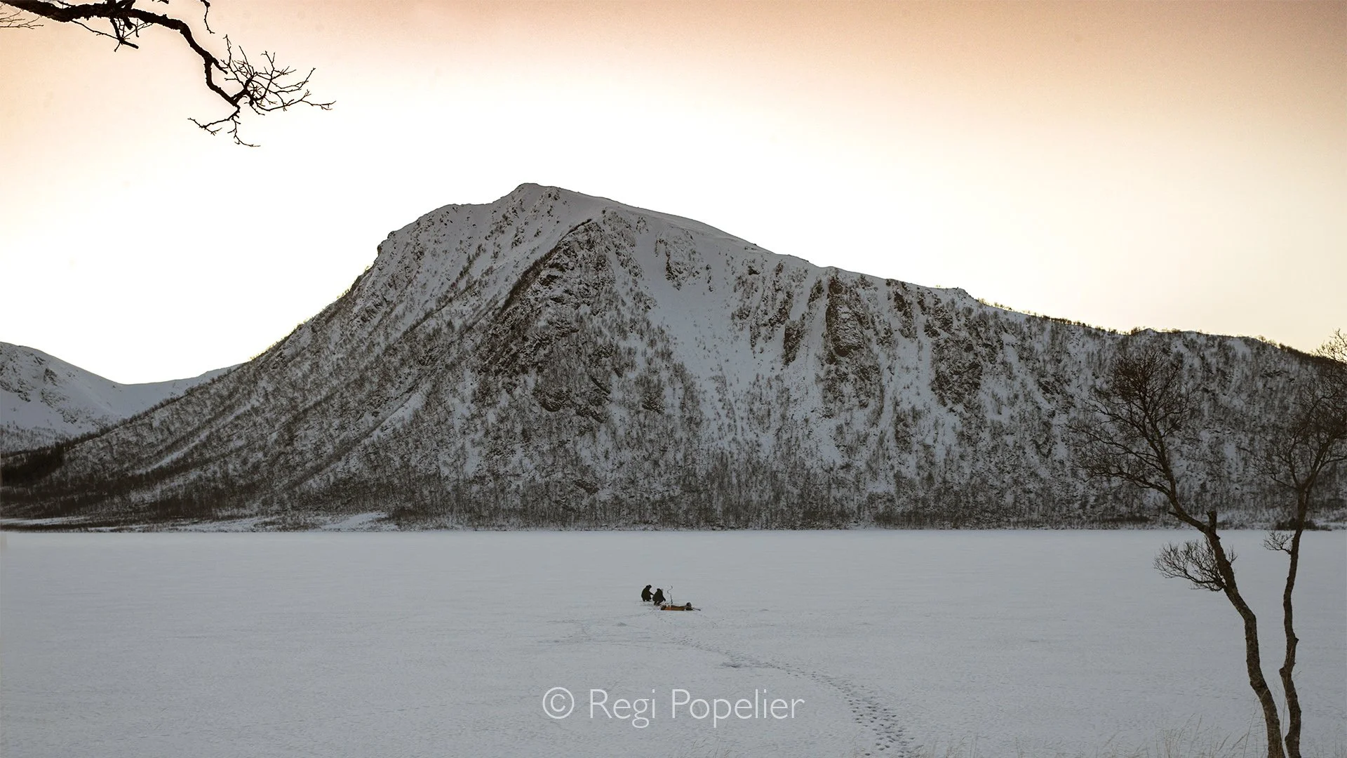 NORWAY002 - Fishermen patiently wait above the frozen lake, where tradition and nature meet beneath an endless winter sky.
