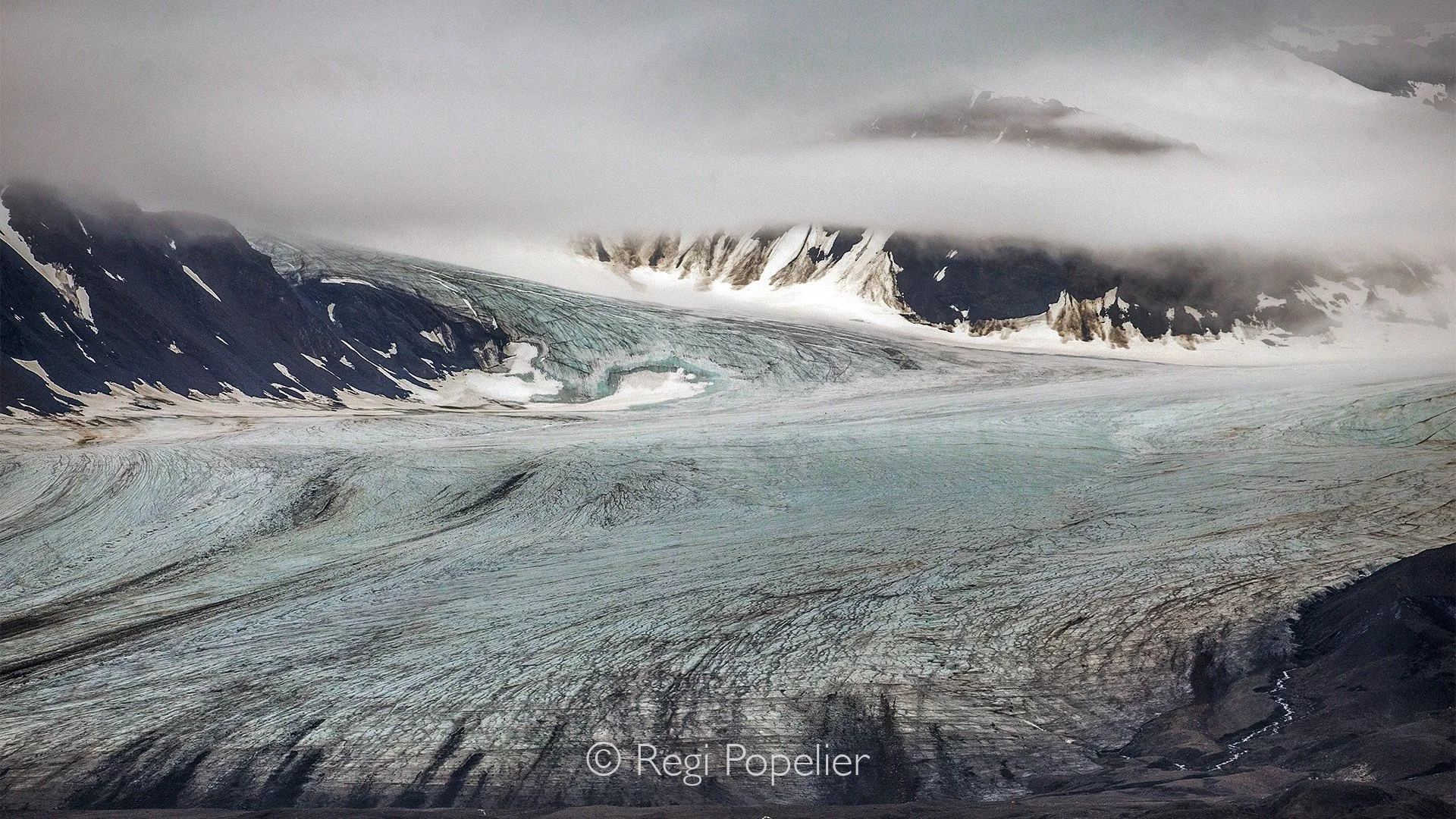 NPOLE006 - A vast glacier descends from the mountains, its ancient ice shaping the Arctic landscape.