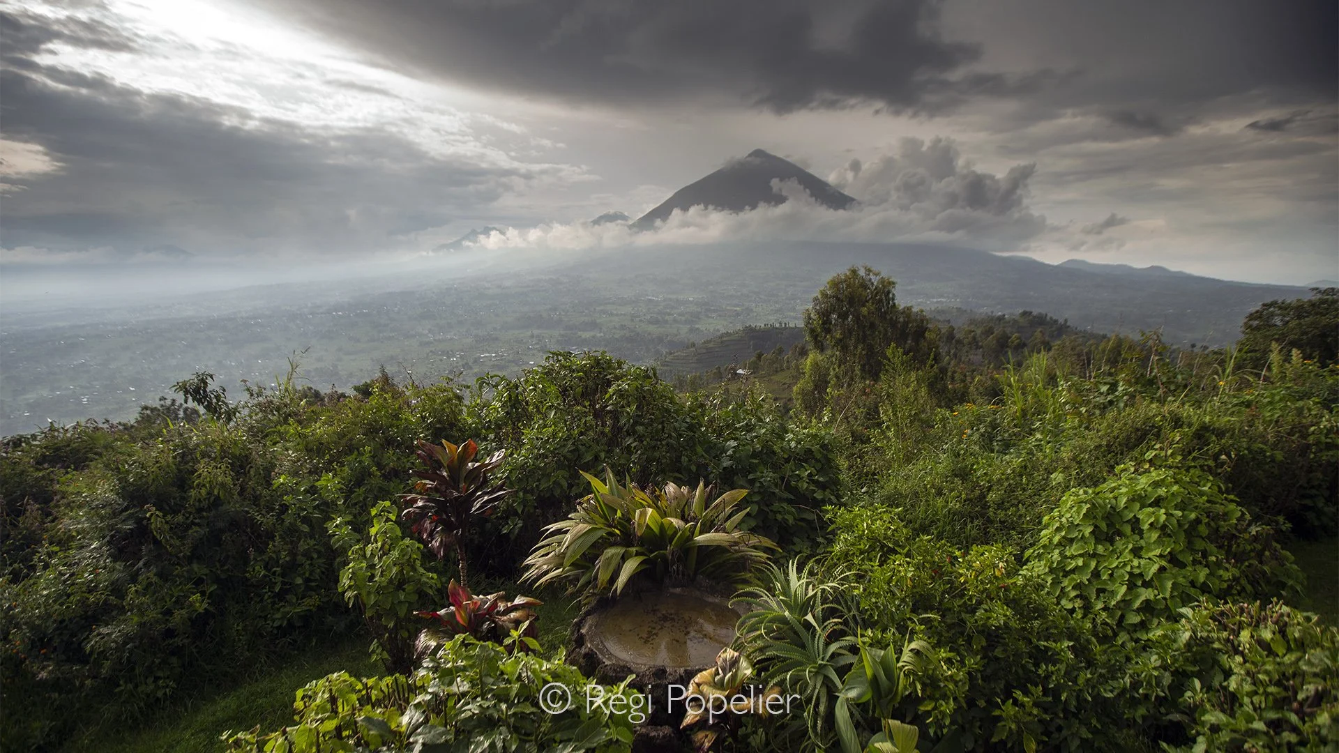 RWANDA036  - Looking out from the lodge, the volcanic silhouettes of the Virunga Mountains dominate the horizon. Their forested slopes disappear into drifting clouds, hiding the home of the world's remaining mountain gorillas.