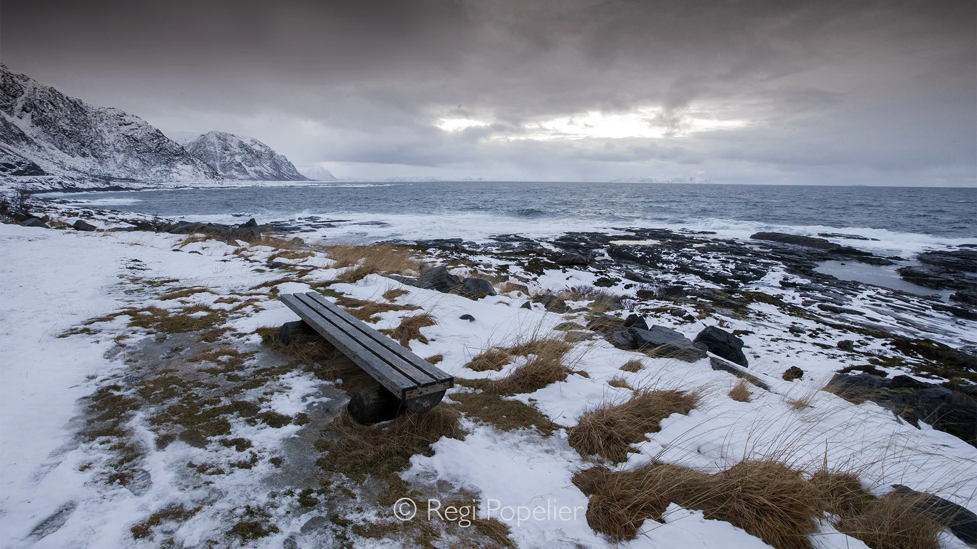 NORWAY009 - A lone wooden bank  stands surrounded by snow, a symbol of warmth in an endless world of ice and silence.
