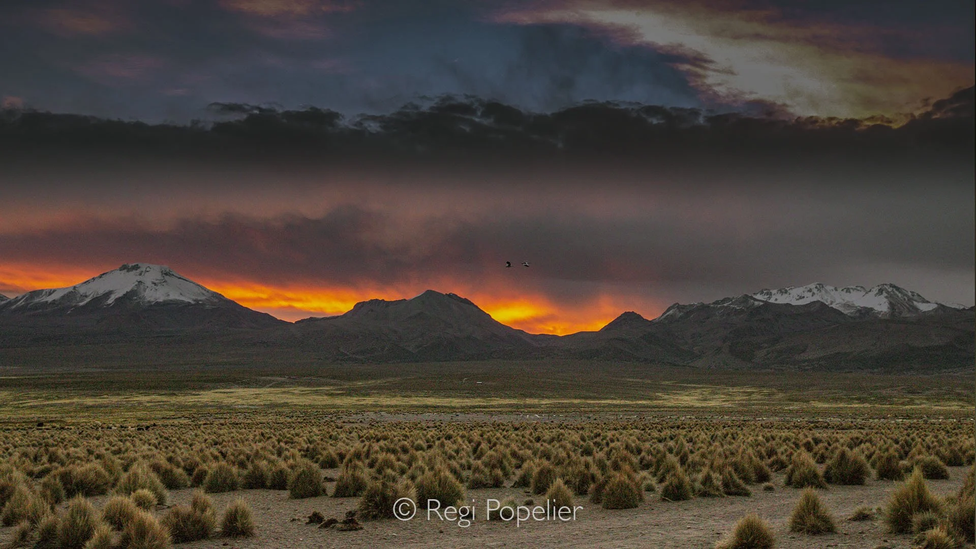 BOL016 - Stunning landscapes along the road at sunset, with red skies glowing above the mountain peaks. Bolivia’s highland beauty at golden hour.