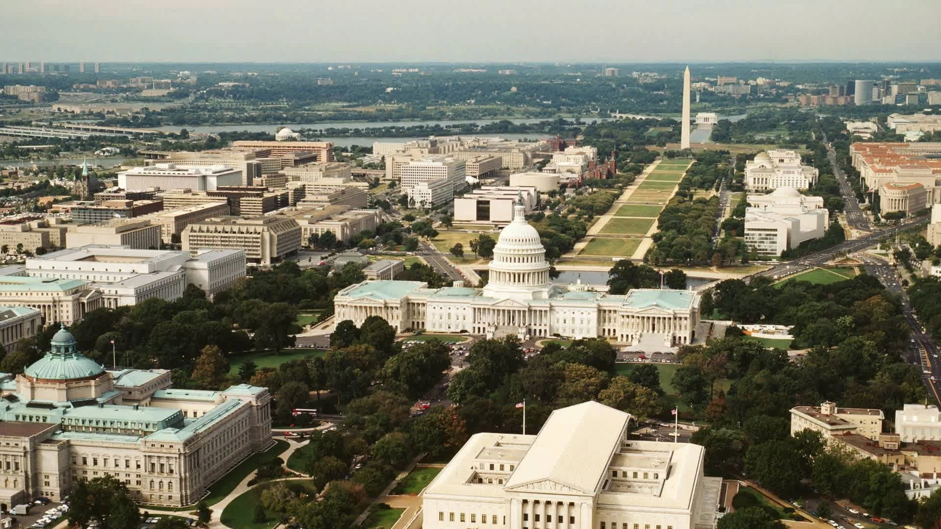 Aerial view of Washington D.C. featuring the Capitol Building, the Washington Monument, and the National Mall with surrounding cityscape.