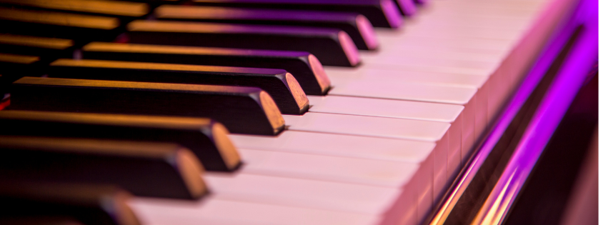 Close-up of piano keys illuminated with purple and pink lighting