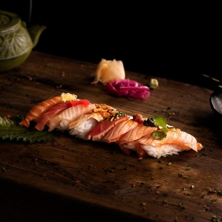 Sushibitar på en träskärbräda med inlagd ingefära och picklad rödlök.