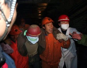 Group of miners wearing helmets and protective gear, inside a dark mine shaft.